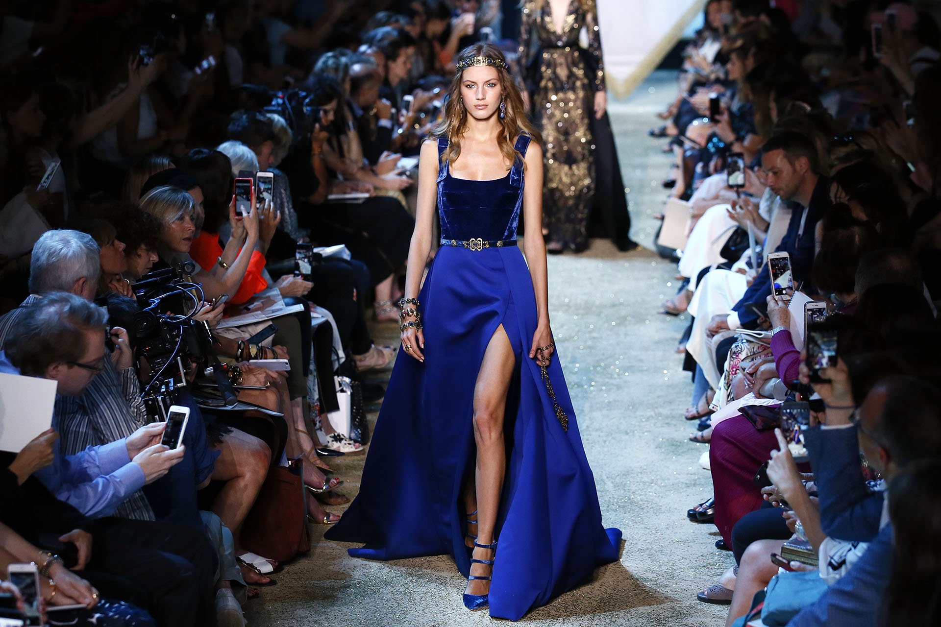 En azul francia, otra de las tonalidades estrellas de la colección. Combinado con el terciopelo, la falda con cola y un gran abertura lateral para darle movimiento. Los accesorios fueron el toque inspirados en la serie (AP Photo/Francois Mori)