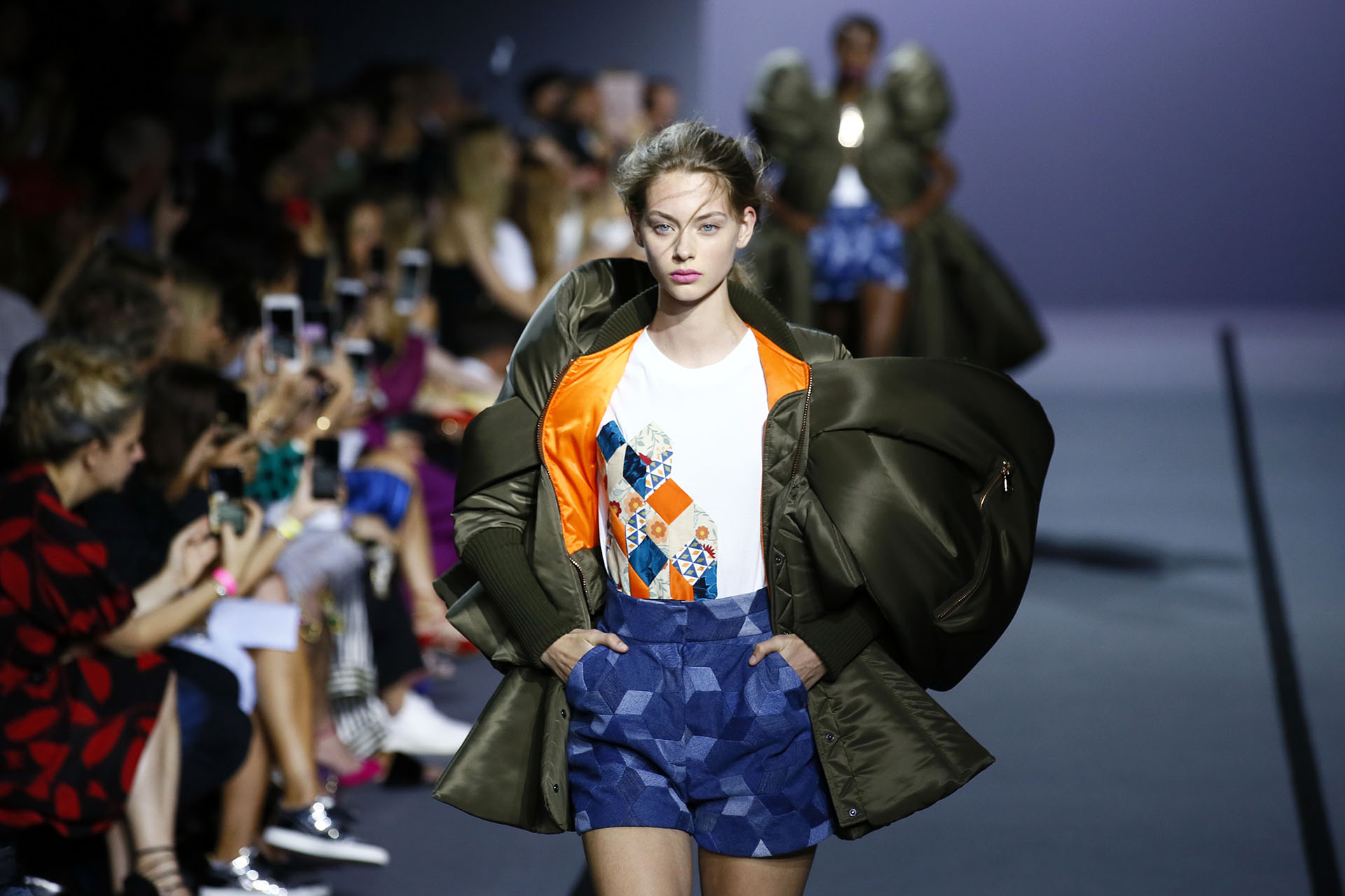 La campera verde militar con una manga acampanada y volumen en la espalda combinado por un conjunto de remera estampada blanca y short ambos geométricos (AP Photo/Francois Mori)