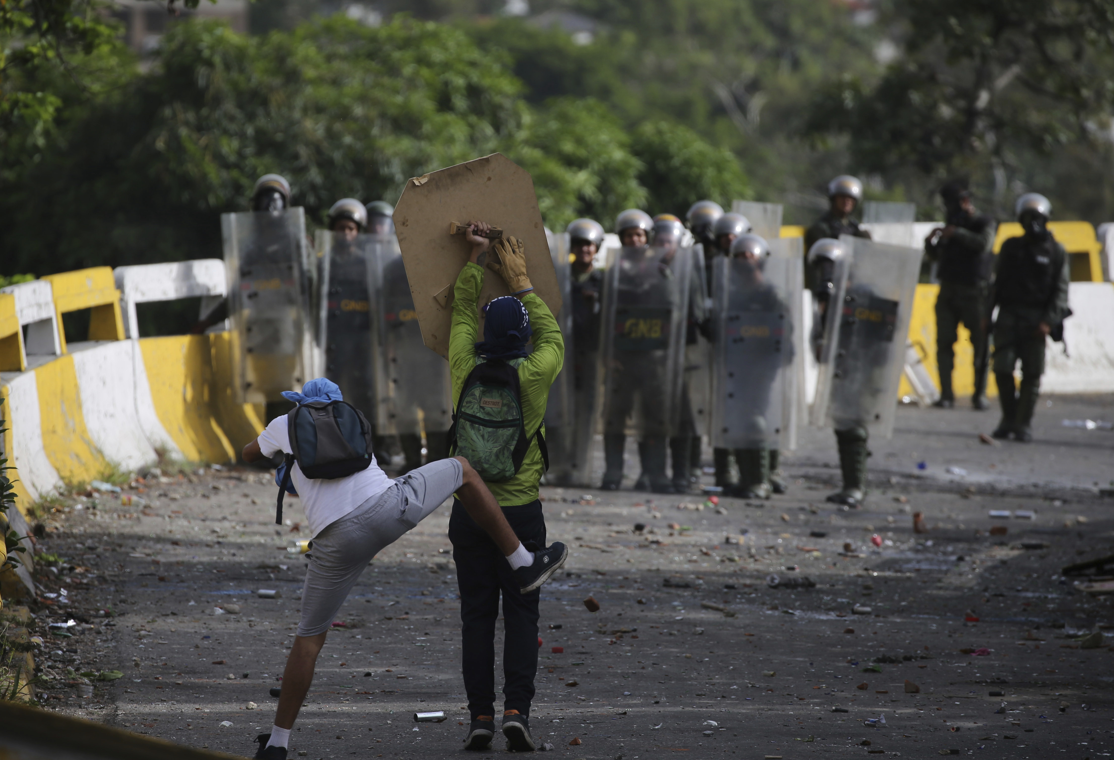 Los manifestantes intentan protegerse de los disparos de los oficiales chavistas