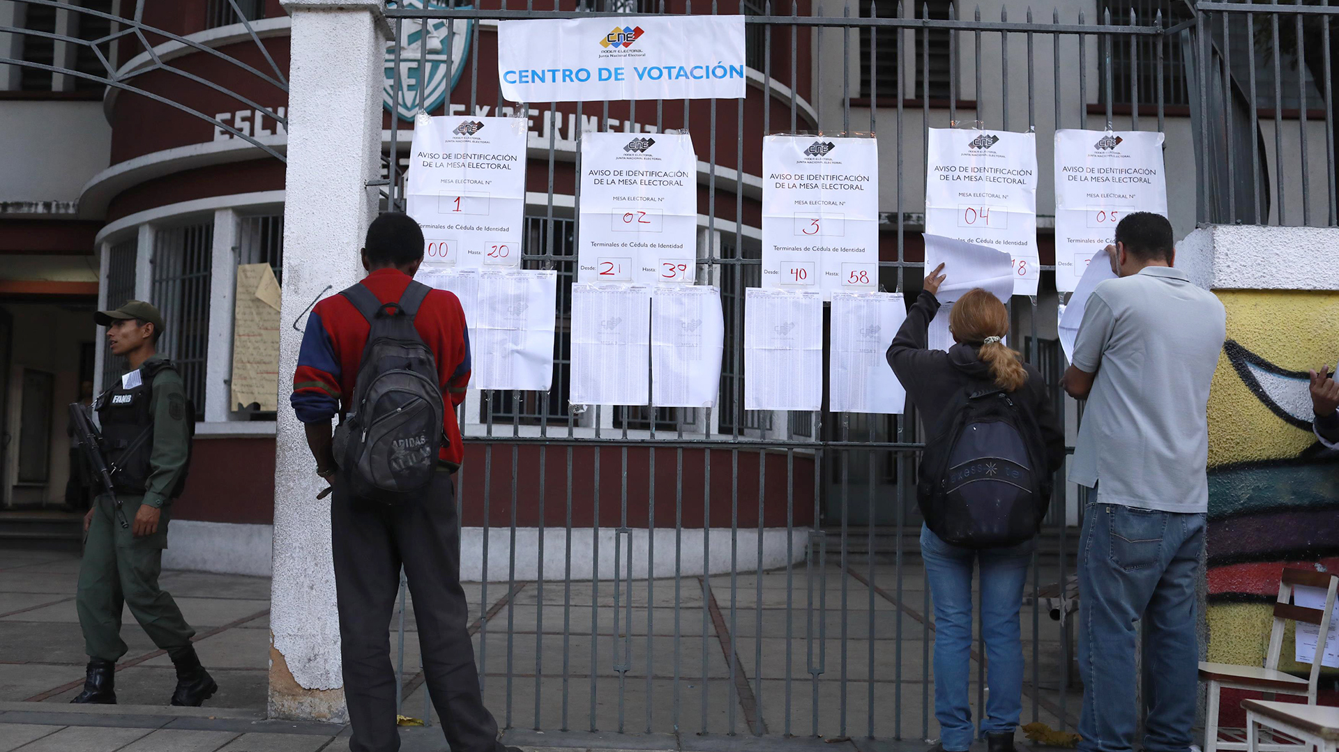 Tres personas revisan las listas antes de votar (Reuters)