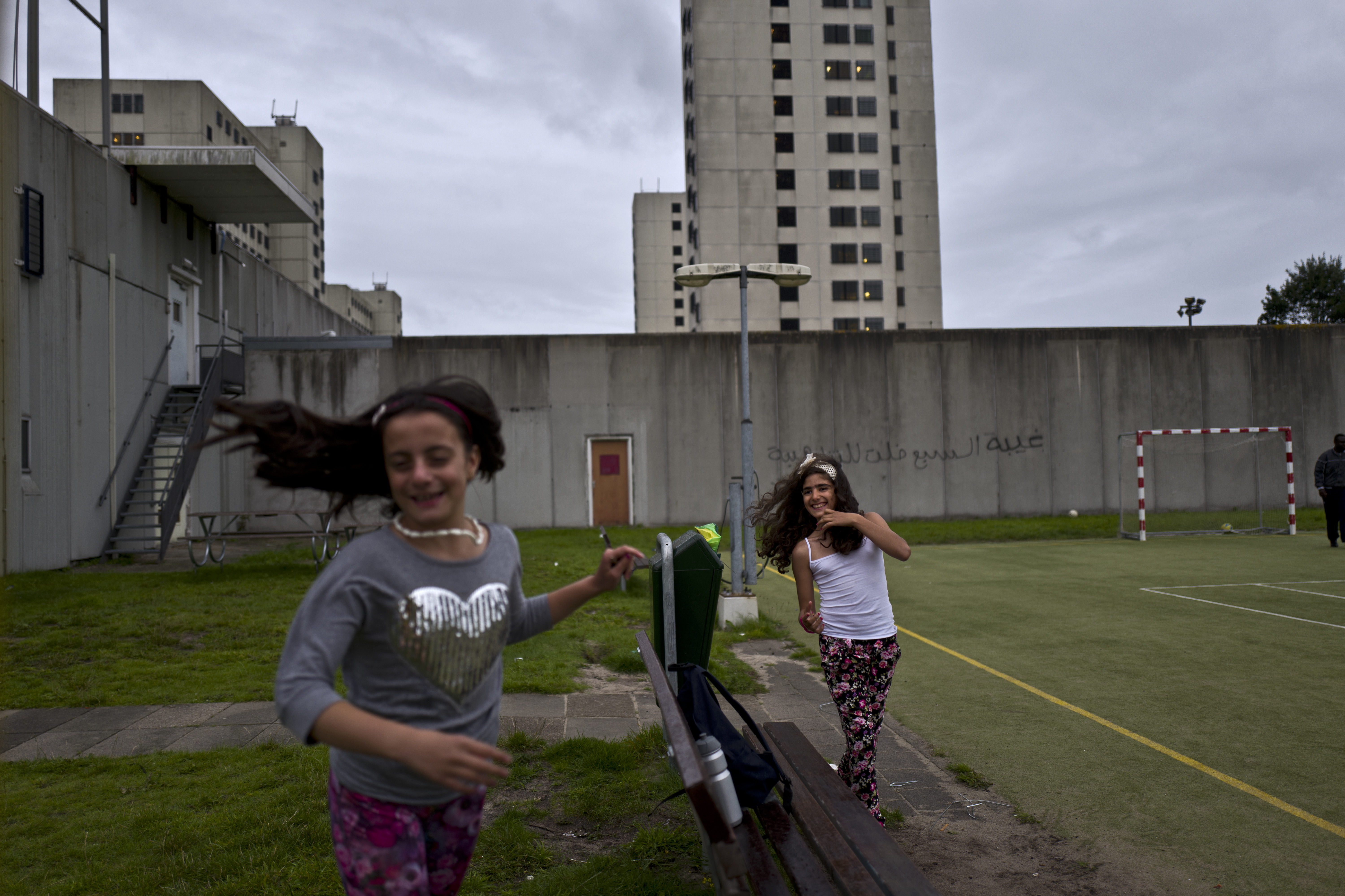 Las niñas sirias Mishleen Samir, de 10 años, y su amiga Claire Alzain, juegan en el campo de la ex cárcel de Bijlmerbajes en Amsterdam (AP Photo/Muhammed Muheisen)
