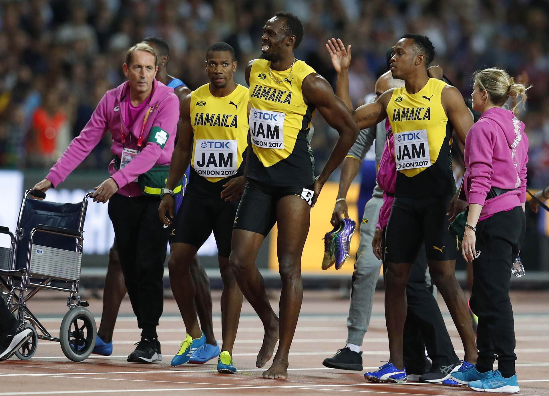 Ya sin zapatillas, Bolt se retira al vestuario acompañado por los médicos y el equipo
