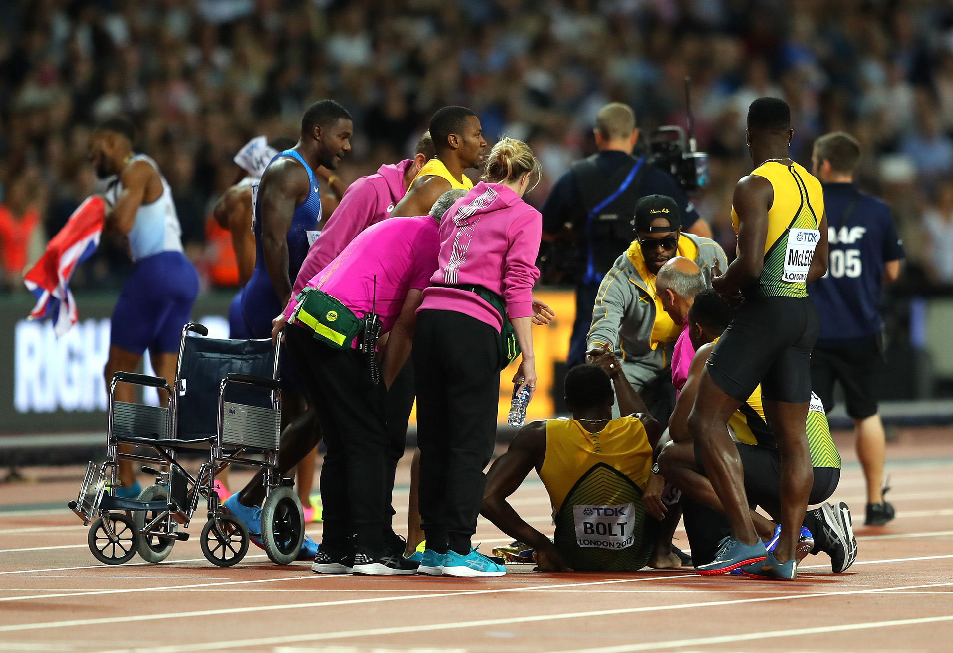 Ayudan a levantarse a Bolt; en el fondo, celebra Gran Bretaña