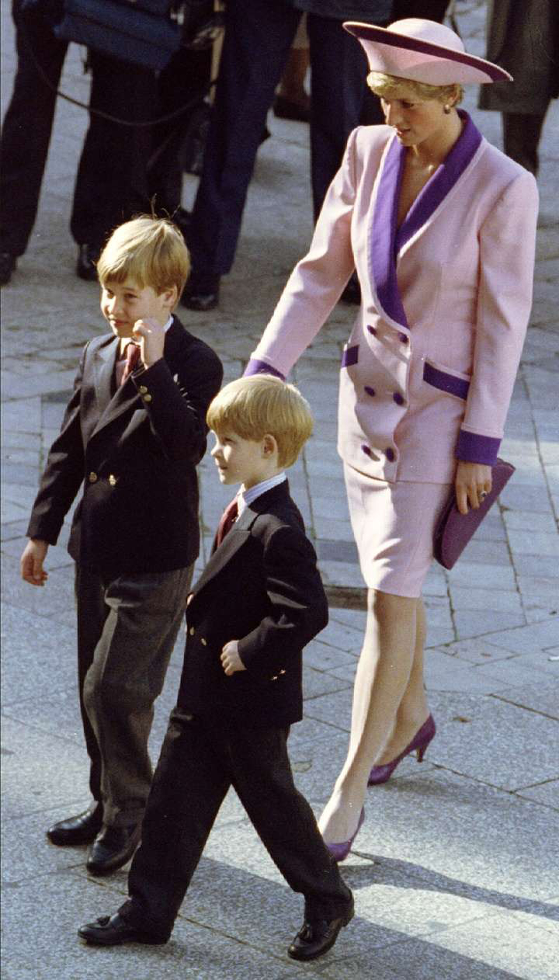 Diana en compañía de sus dos hijos, ambos luciendo trajes con camisa y corbata. Ella con tallieur en falda y bicolor en rosa pastel y violeta