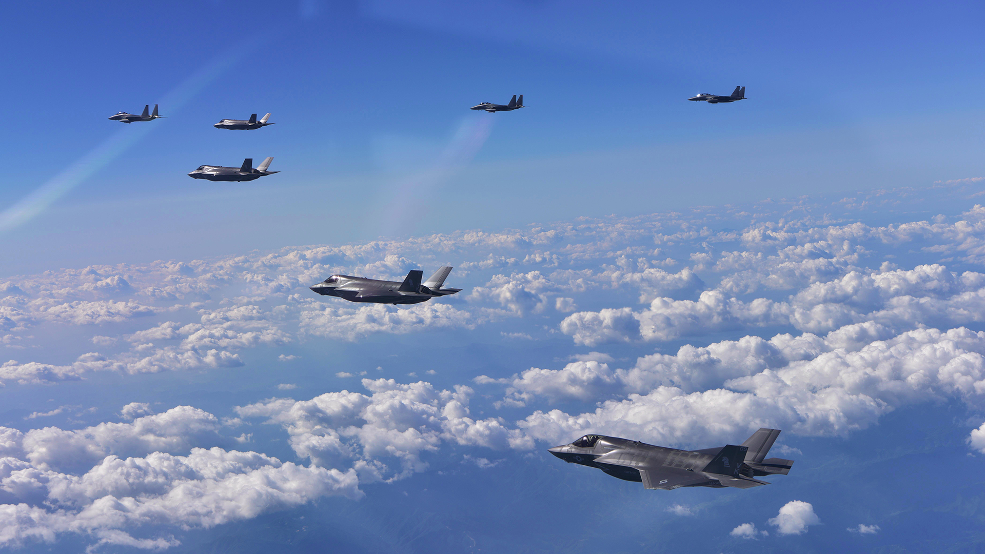 Tres cazas F-15K surcoreanos, en el fondo, y cuatro F-35B furtivos de la fuerza aérea de Estados Unidos (AFP)