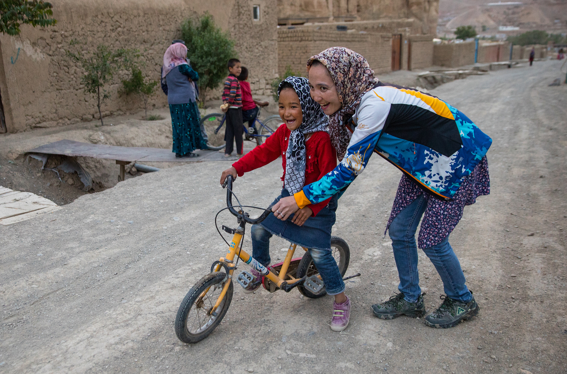 Zakia Mohammadhi, de 23 años de edad, empuja a su hermana menor, Honey, de 7 años de edad en bicicleta hasta su casa, que se encuentra en un camino de tierra hasta una colina que puede ser todo un reto para un niño. (Paula Bronstein)