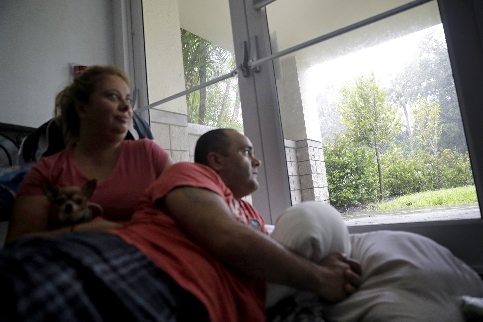 Javier García y su esposa Marissa Soto se sientan con el perro de su vecino Ilito mientras pasan el huracán Irma en un refugio en Nápoles, Florida, el domingo 10 de septiembre de 2017. (AP)