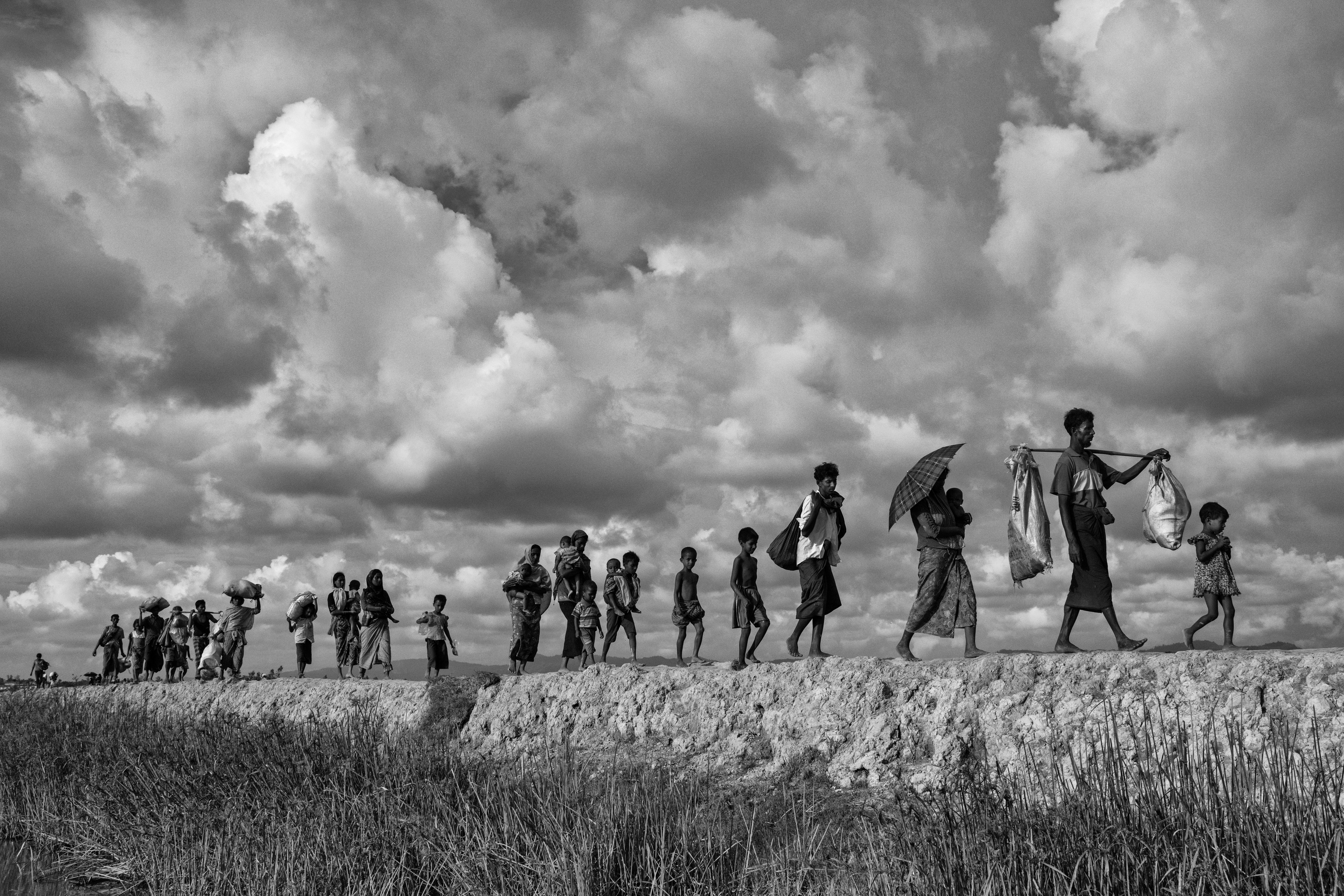 Refugiados rohinyás cargan sus pertenencias mientras cruzan la frontera entre Myanmar y Bangladesh (Kevin Frayer/Getty Images)