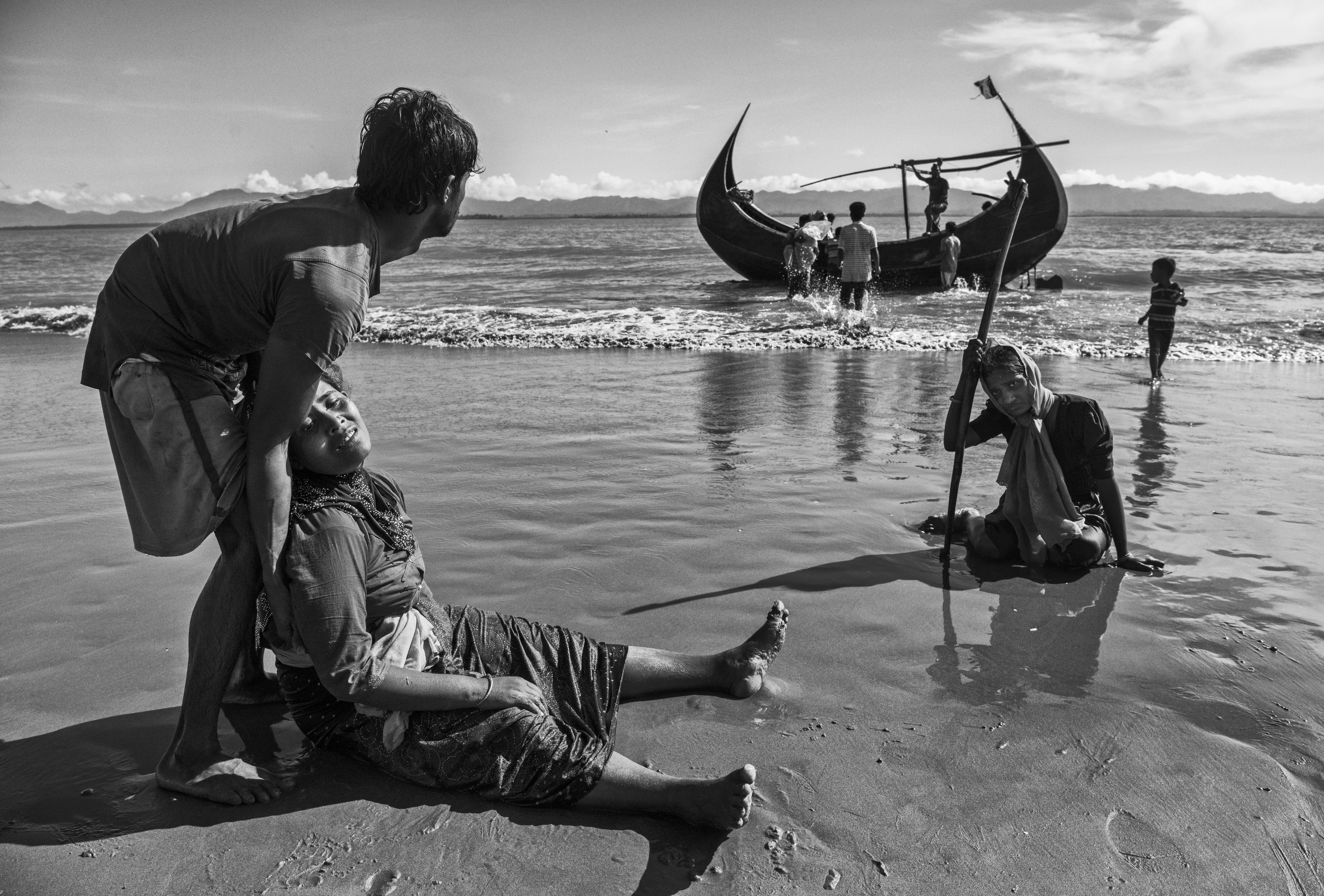 Una mujer descansa agotada en la playa del río Naf, en Shah Porir Dwip, tras escapar de su aldea en Myanmar (Kevin Frayer/Getty Images)