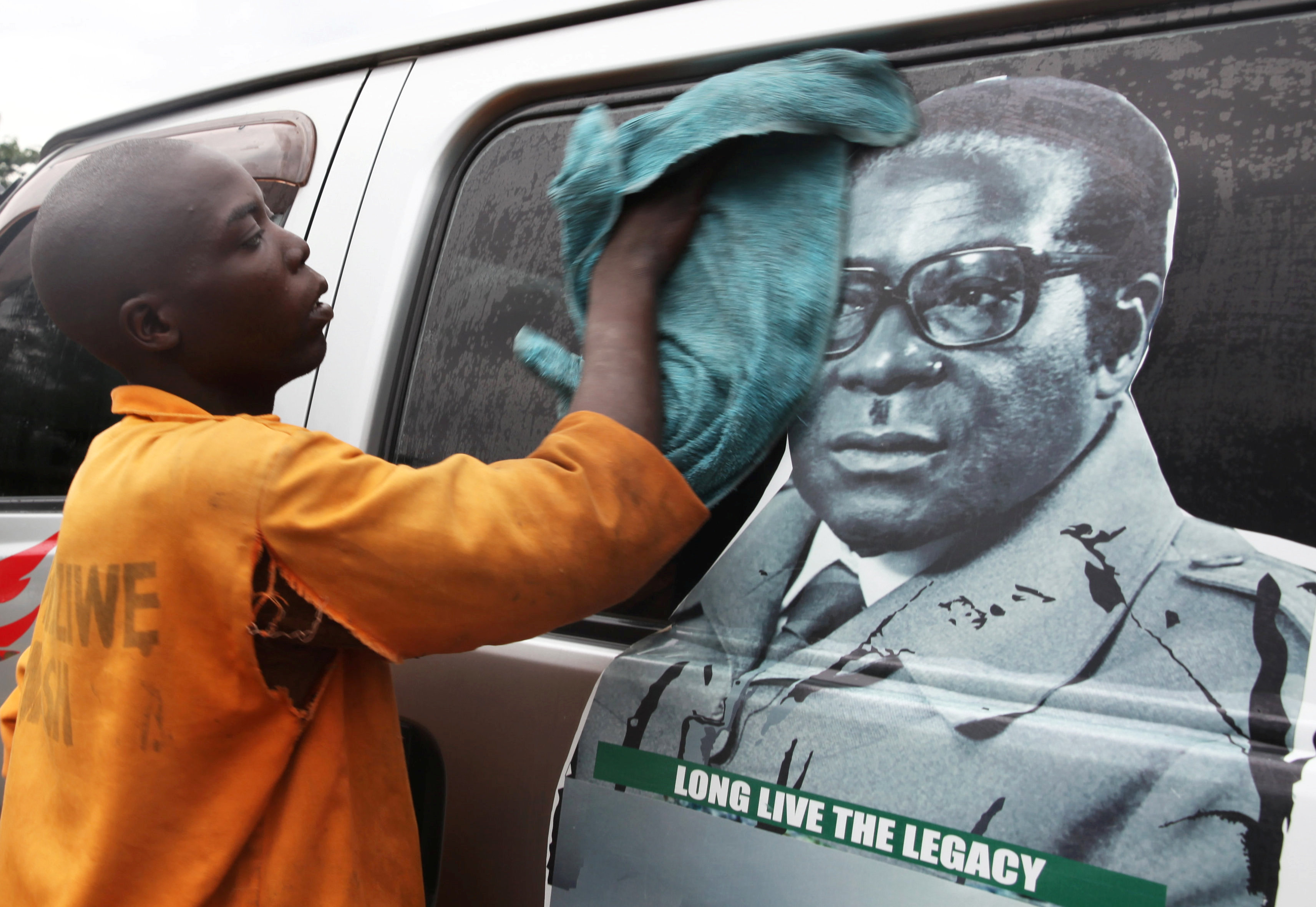 Un joven limpia un minibus con una foto de Mugabe en Harare, el 15 de noviembre de 2017 (REUTERS/Philimon Bulawayo)