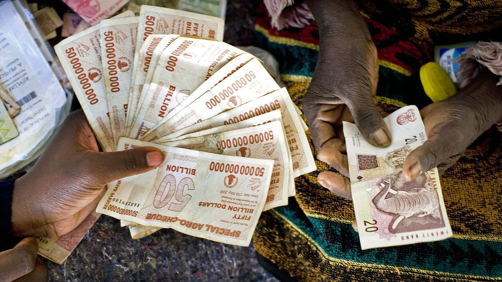 La hiperinflación hizo que la moneda de Zimbabwe resultara inútil después del cambio de milenio y fue finalmente desechada. El país ahora utiliza principalmente el dólar estadounidense y se enfrenta a una gran escasez de efectivo. Aquí varias denominaciones del dólar de Zimbabwe se muestran junto a una nota sudafricana de 20 rands en Harare en 2009.