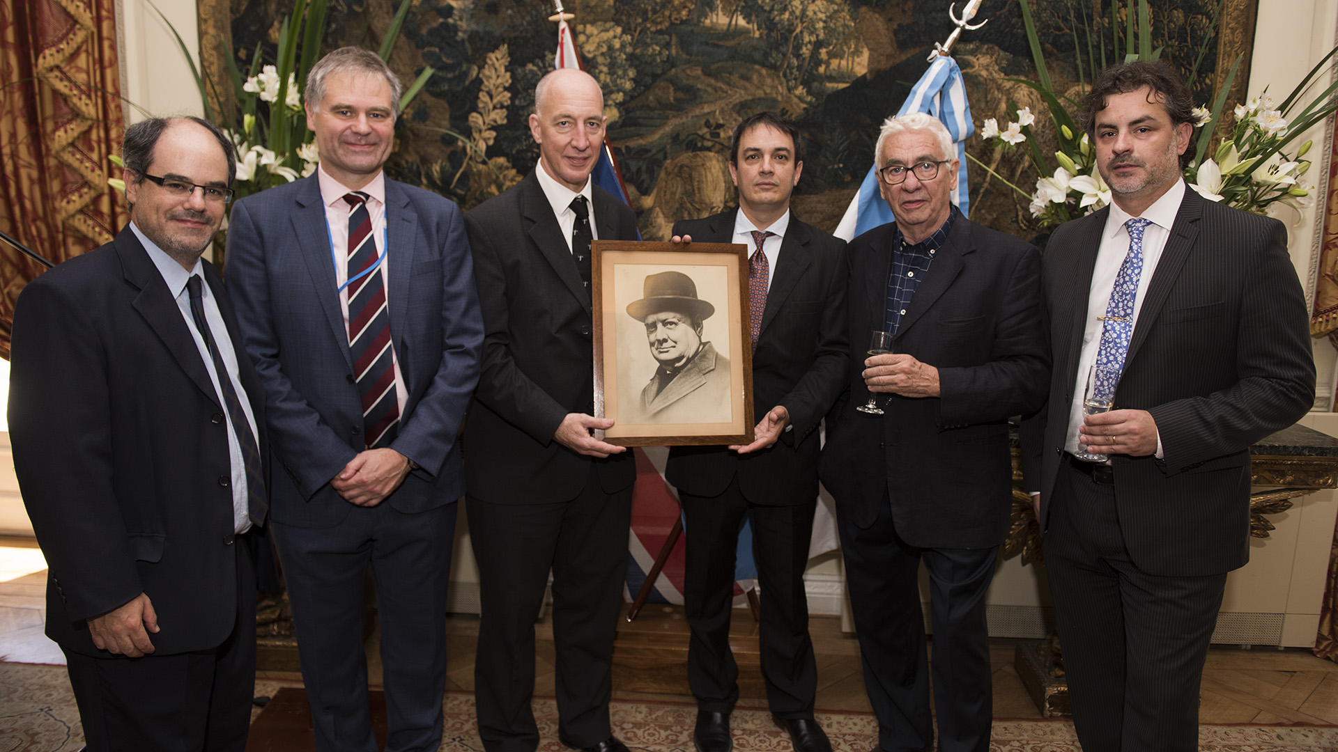 Oliver Galak, director de Comunicación de la embajada británica; Robin Smith, Agregado de Defensa; el embajador Mark Kent; el historiador Nelson Durante y el orfebre Juan Carlos Pallarols con una fotografía de Winston Churchill que perteneció a la casa original y hoy volvió a la Residencia Británica