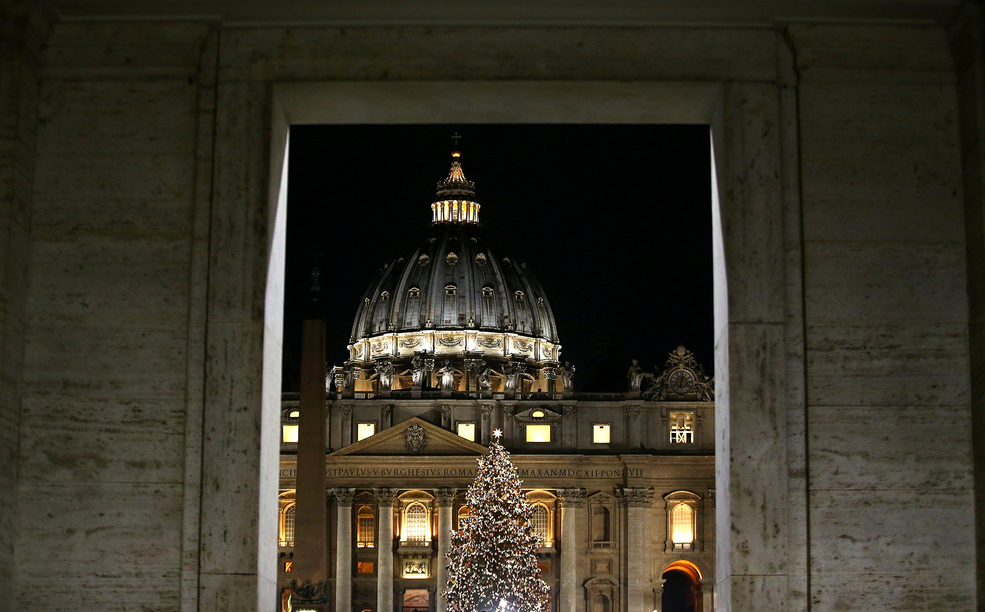 Una imagen del árbol del Vaticano iluminado con la tradicional cúpula detrás