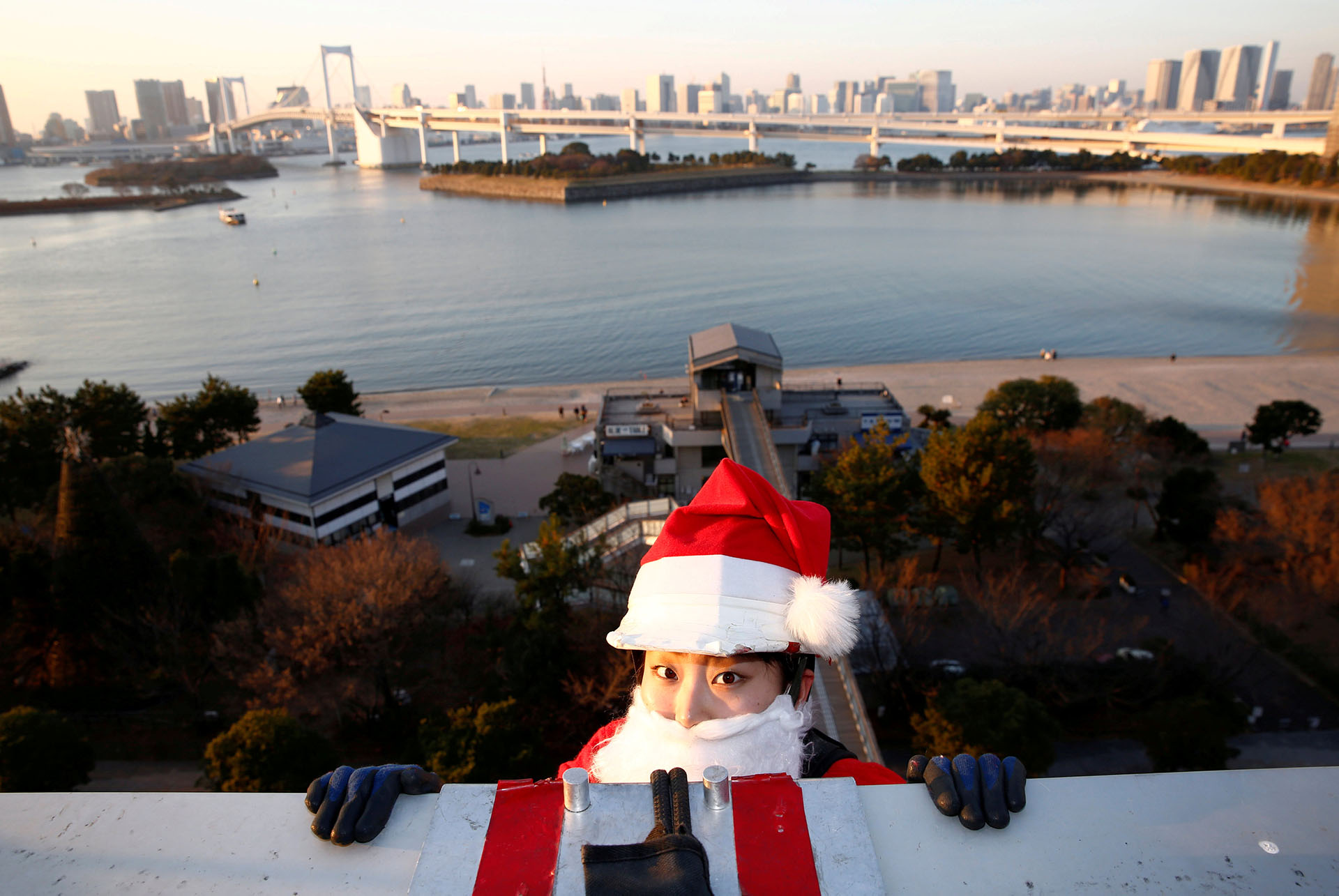 Una limpiadora de ventanas femenina vestida como Santa Claus se prepara para limpiar una ventana de vidrio en un evento para celebrar la próxima Navidad en DECKS Tokyo Beach en Tokio, Japón, el 21 de diciembre de 2017. (Reuters)