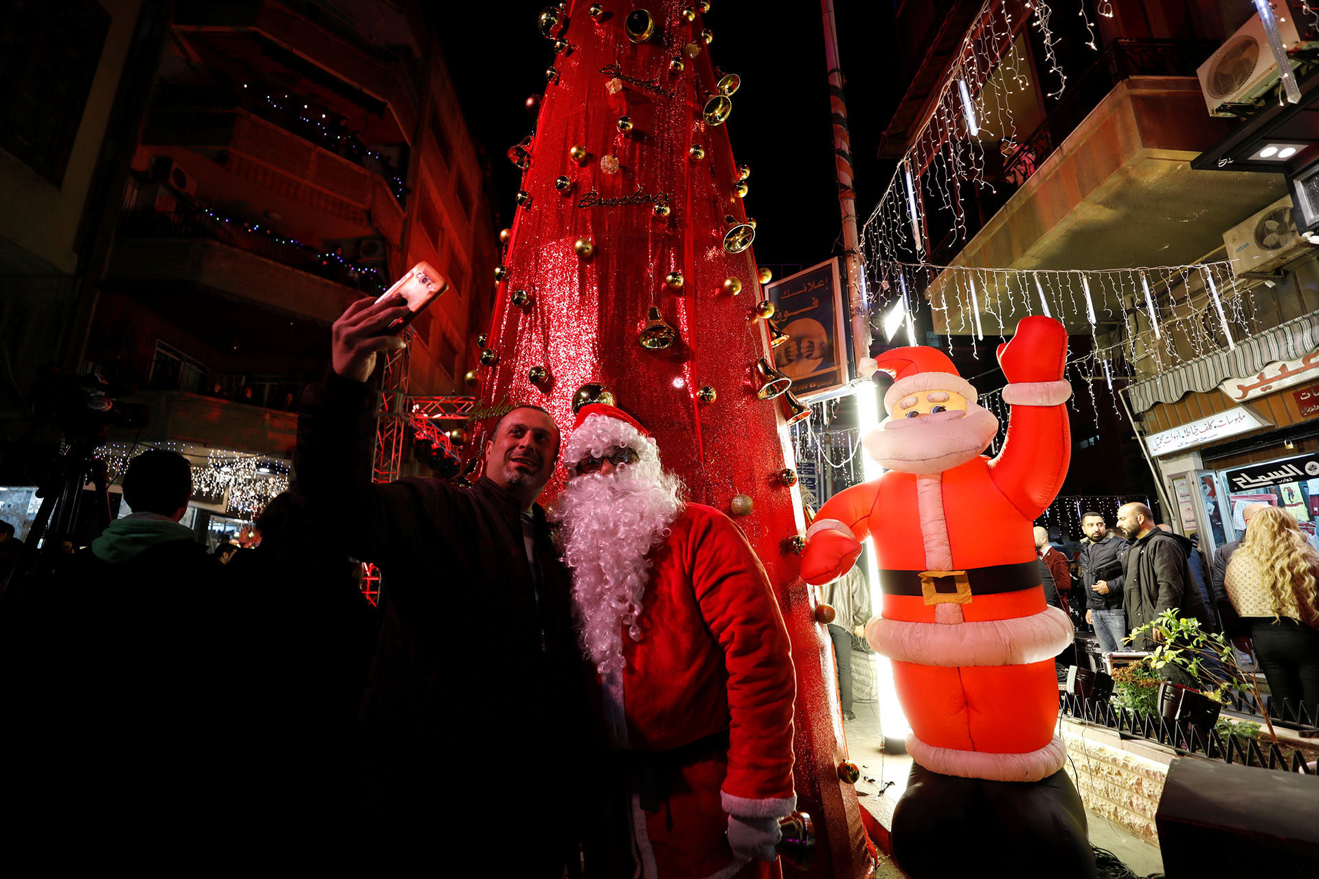 Un hombre se toma una selfie con un hombre vestido como Papá Noel durante un festival de Navidad en Damasco, Siria, el 20 de diciembre de 2017. (Reuters)