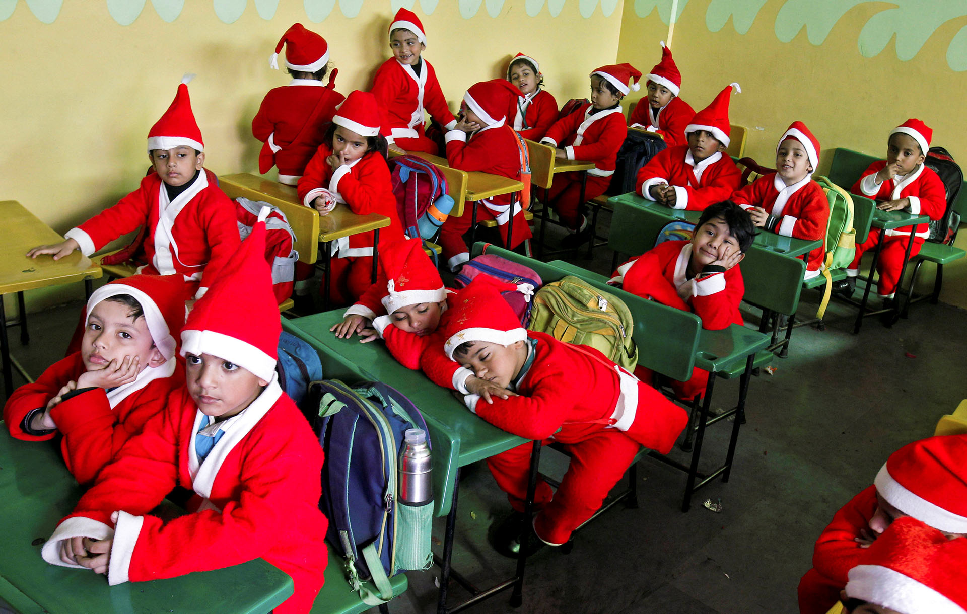 Niños vestidos con trajes de Santa Claus se sientan dentro de un aula antes de participar en las celebraciones navideñas en una escuela de Chandigarh, India, el 20 de diciembre de 2017. (Reuters)