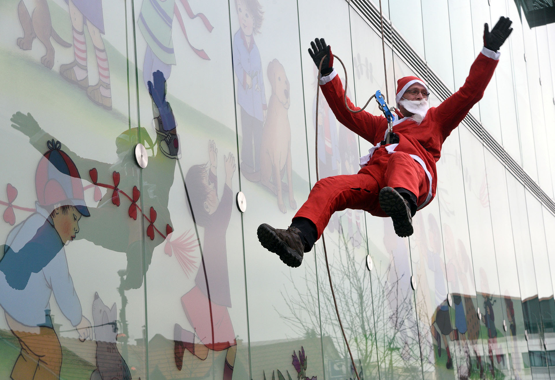 Un miembro del Servicio de Rescate de Montaña vestido con un traje de Papá Noel se acerca a los pacientes mientras desciende del techo de una clínica pediátrica en Ljubljana, Eslovenia, el 19 de diciembre de 2017. (Reuters)
