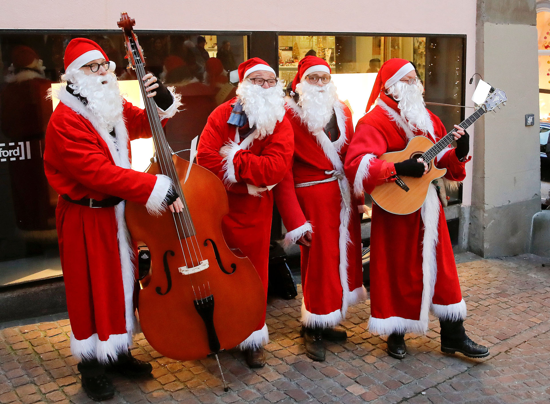 Los miembros del cuarteto vocal de jazz navideño Singing Santas actúan en la ciudad vieja de Zúrich, Suiza, el 17 de diciembre de 2017. (Reuters)