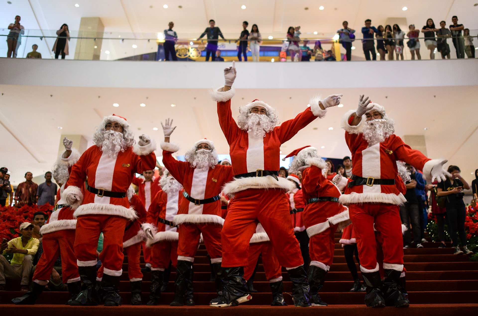 Intérpretes vestidos con trajes de Santa Claus bailan en un centro comercial en Kuala Lumpur el 18 de diciembre de 2017. (AFP)