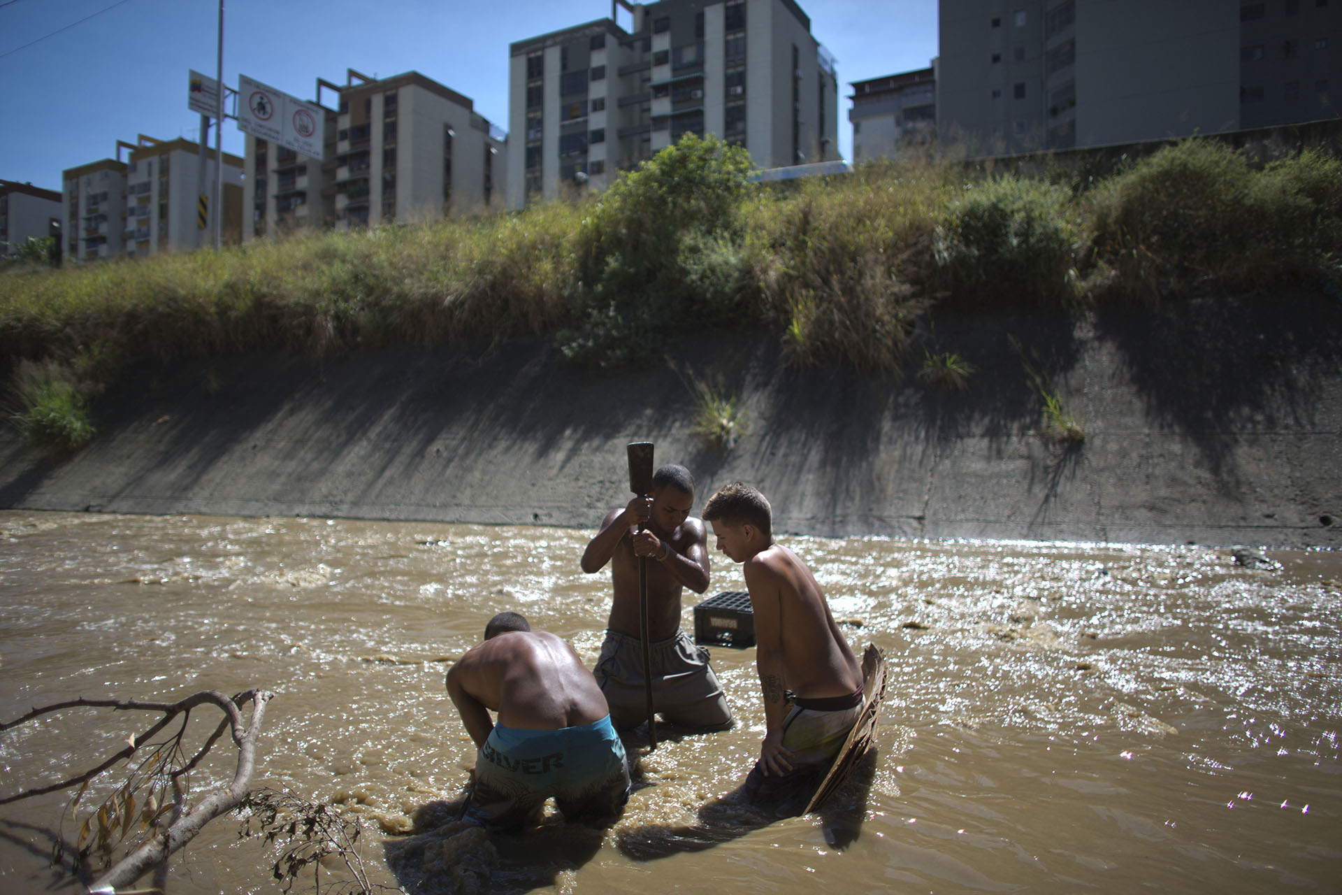 Angel Villanueva, al centro, usa una barra de metal para golpear el barro y separarlo, en búsqueda de piezas con algo de valor