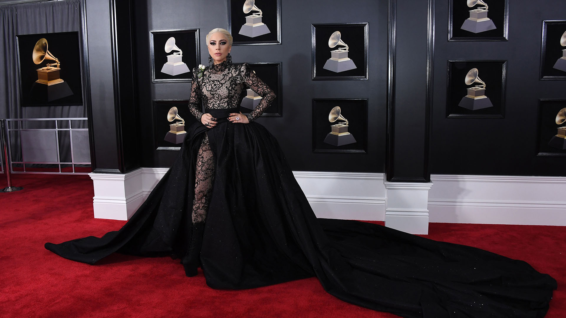 Lady Gaga con un catsuit negro de encaje y una sobrefalda negra voluptuosa abullonada con botas de taco y plataforma XL