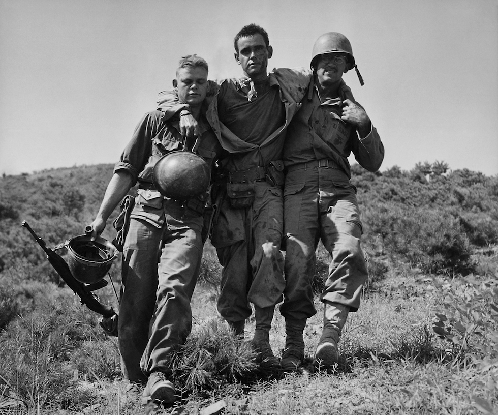 Un marine herido ayudado por dos compañeros en Nakdong, en Corea del Sur, agosto de 1950(AP Foto/Max Desfor, File)