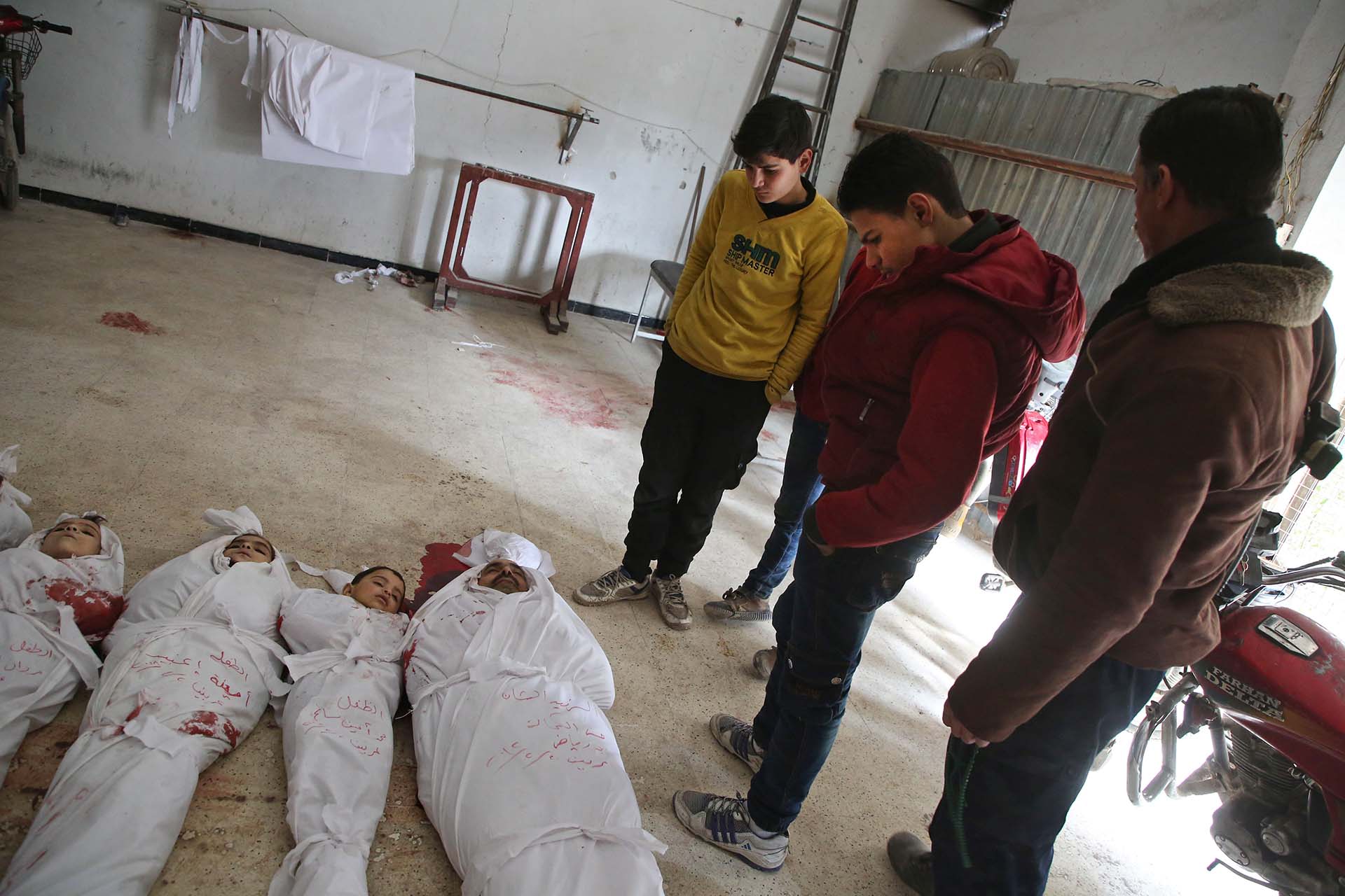 Los cadáveres yacen sobre el suelo, tapados con sábanas y manchados de sangre (AFP)