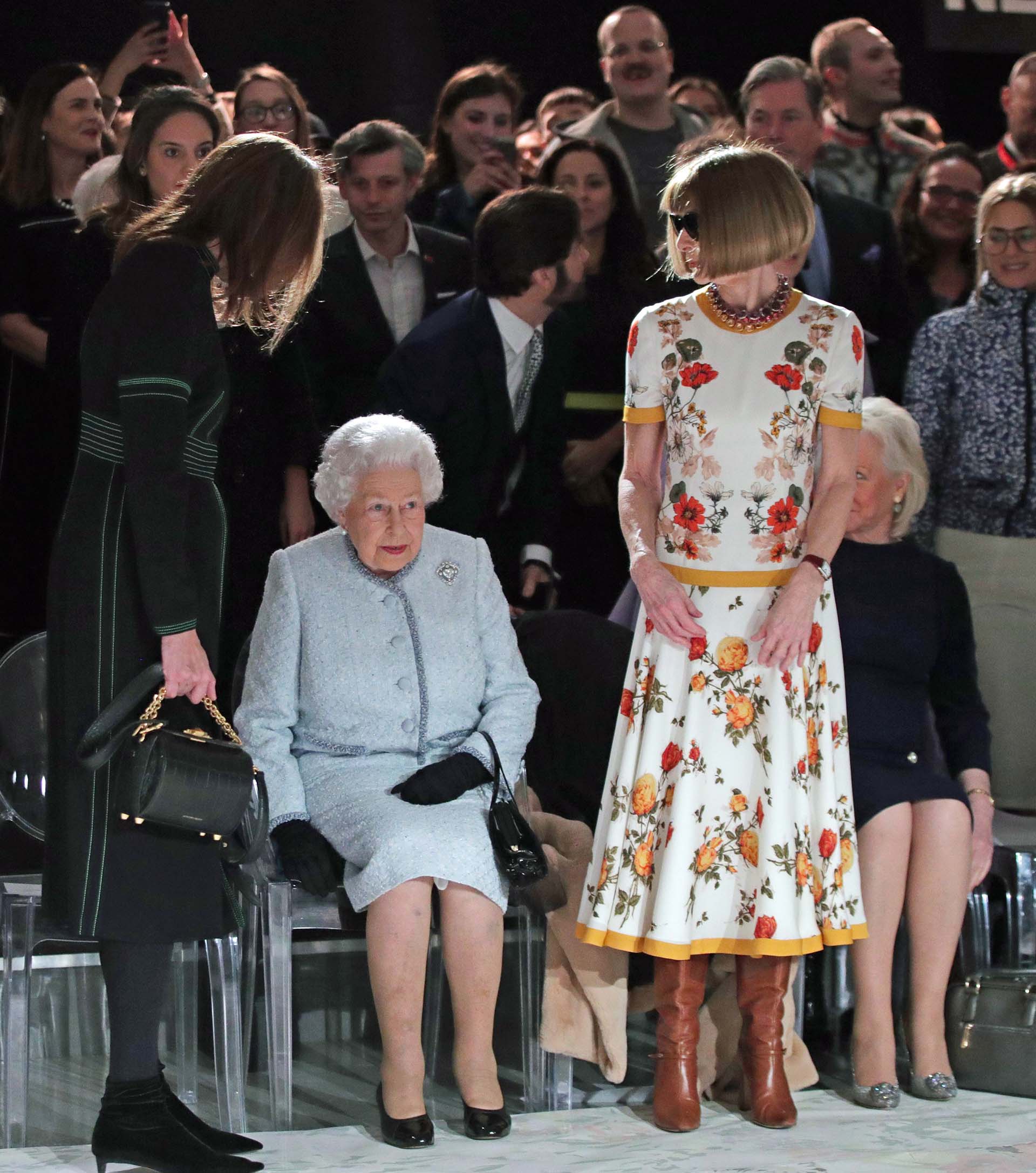 Una de las mujeres más poderosas del ambiente comparte lugar junta a la Reina Isabel II, expectantes antes de la presentación de la firma italiana: Gucci