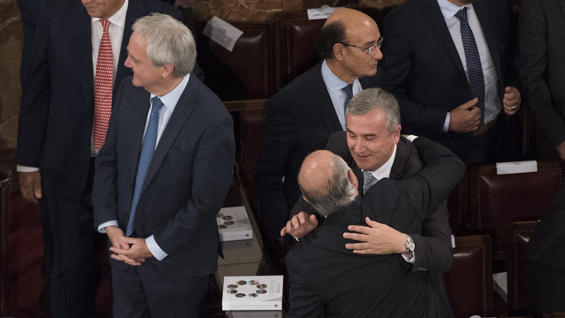 Pinedo rie en el fondo, mientras Gerardo Morales saluda a un legislador
