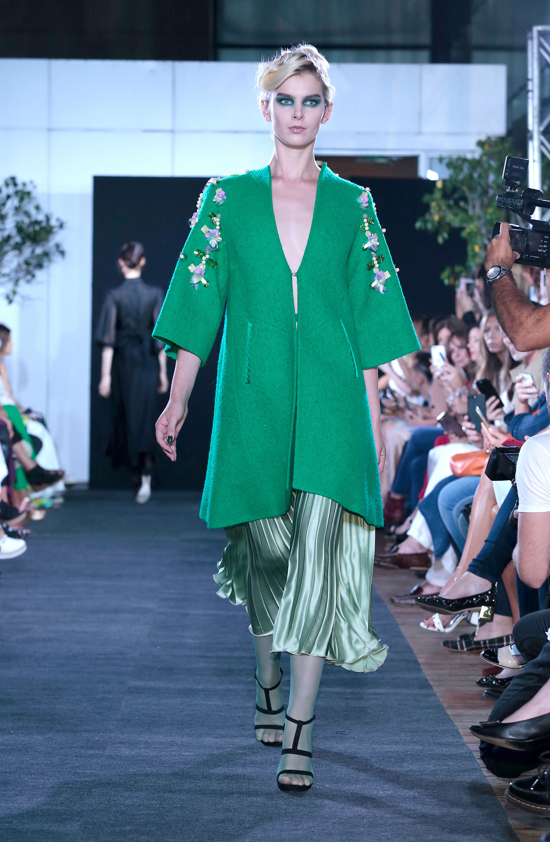 Tapado de paño en verde esmeralda con bordado de flores, un must. Debajo, una falda midi plisada en verde pastel metalizado