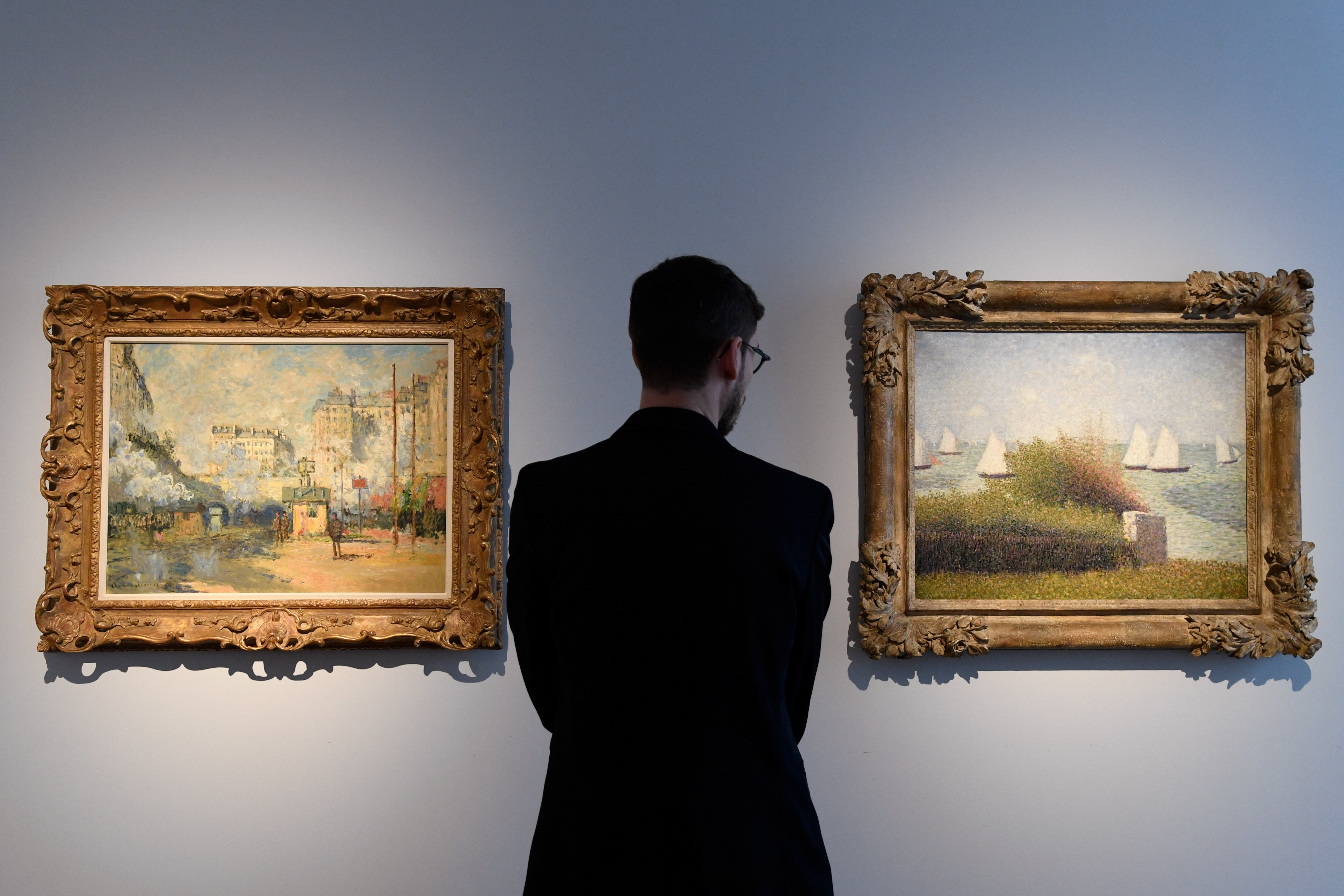 Un hombre observa una de las famosas pinturas de Saint-Lazare del francés Claude Monet (1877), y la obra “La rade de Grancamp” (1877) de Georges Seurat, estimadas en hasta USD 25 millones