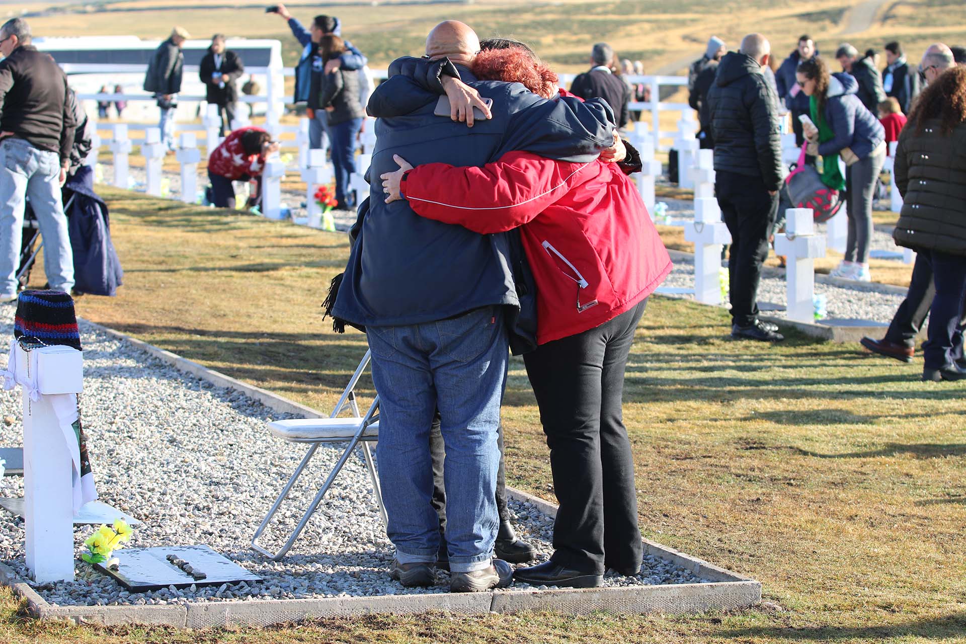 El abrazo del alma. Santiago y María Reyes Lobos, hermanos de José Antonio, soldado caído en la defensa final de Puerto Argentino, se funden con Gaby Cociffi, periodista de Infobae y quien trabajó en la identificación de los cuerpos junto al veterano Julio Aro.