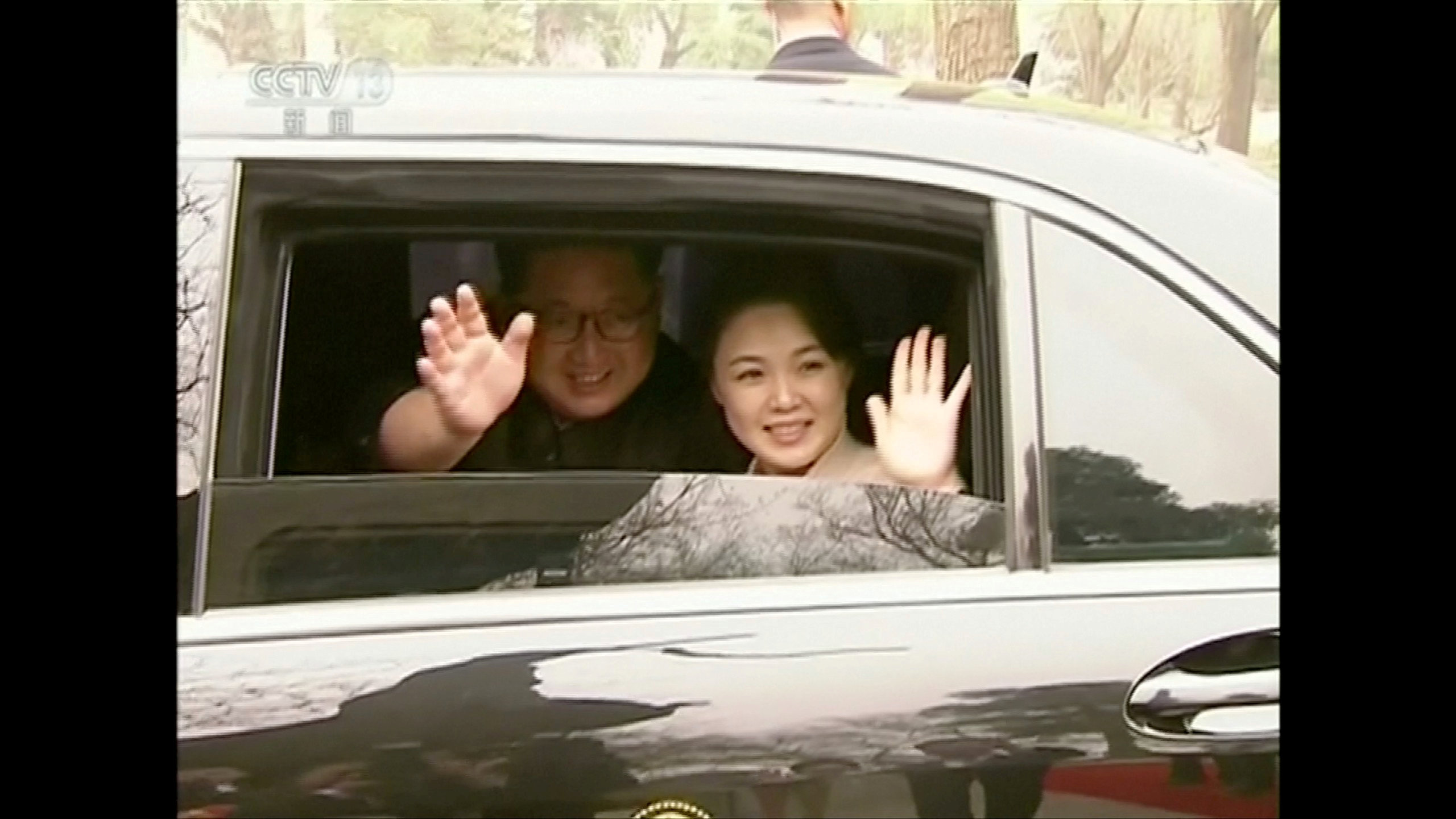 Kim Jong Un y Ri Sol Ju saludan sonrientes desde el vehículo que los trasladó en Beijing