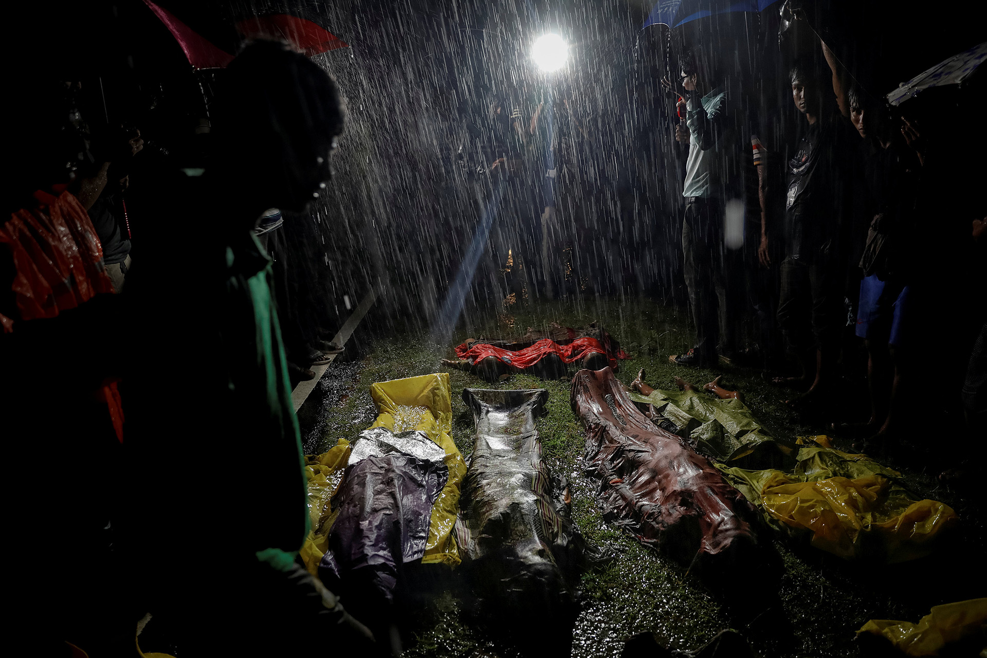 La gente se junta bajo fuertes lluvias alrededor de cuerpos de refugiados Rohingya después de que el bote que usaban para huir de la violencia en Myanmar se hundiera en Inani Beach cerca de Cox’s Bazar, Bangladesh 28 de septiembre de 2017. (Damir Sagolj)