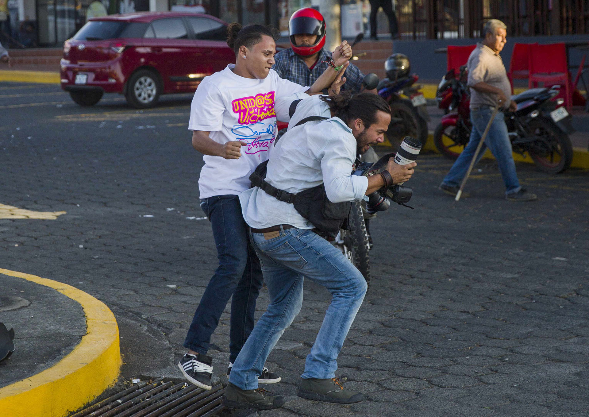 Un miembro de la juventud sandinista forcejea con el reportero gráfico de la agencia de noticias AP Alfredo Zuniga durante las protestas en contra de las reformas del Instituto Nicaragüense de Seguridad Social (INSS), en Managua (EFE/Jorge Torres)