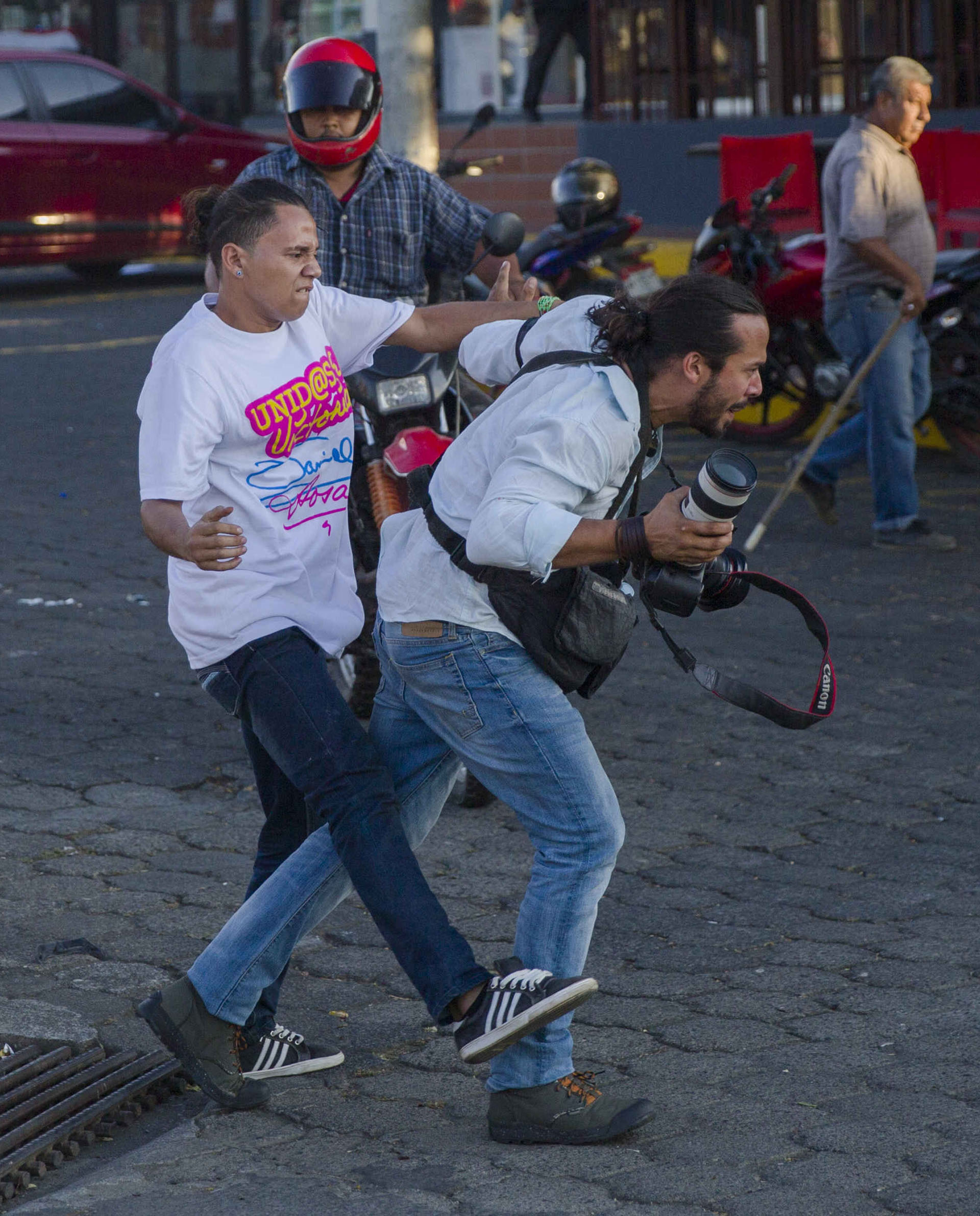 Un miembro de la juventud sandinista agrede al reportero gráfico de la agencia de noticias AP Alfredo Zuniga, mientras cubría la manifestación.