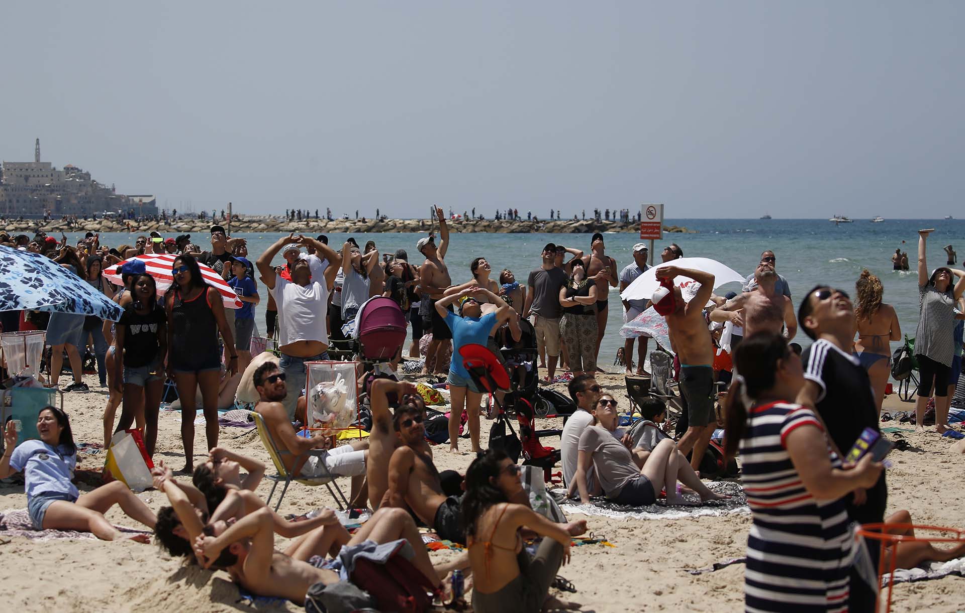 Decenas de israelíes y turistas observan cómo sobrevuelan los aviones militares del Ejército (AFP PHOTO / AHMAD GHARABLI)