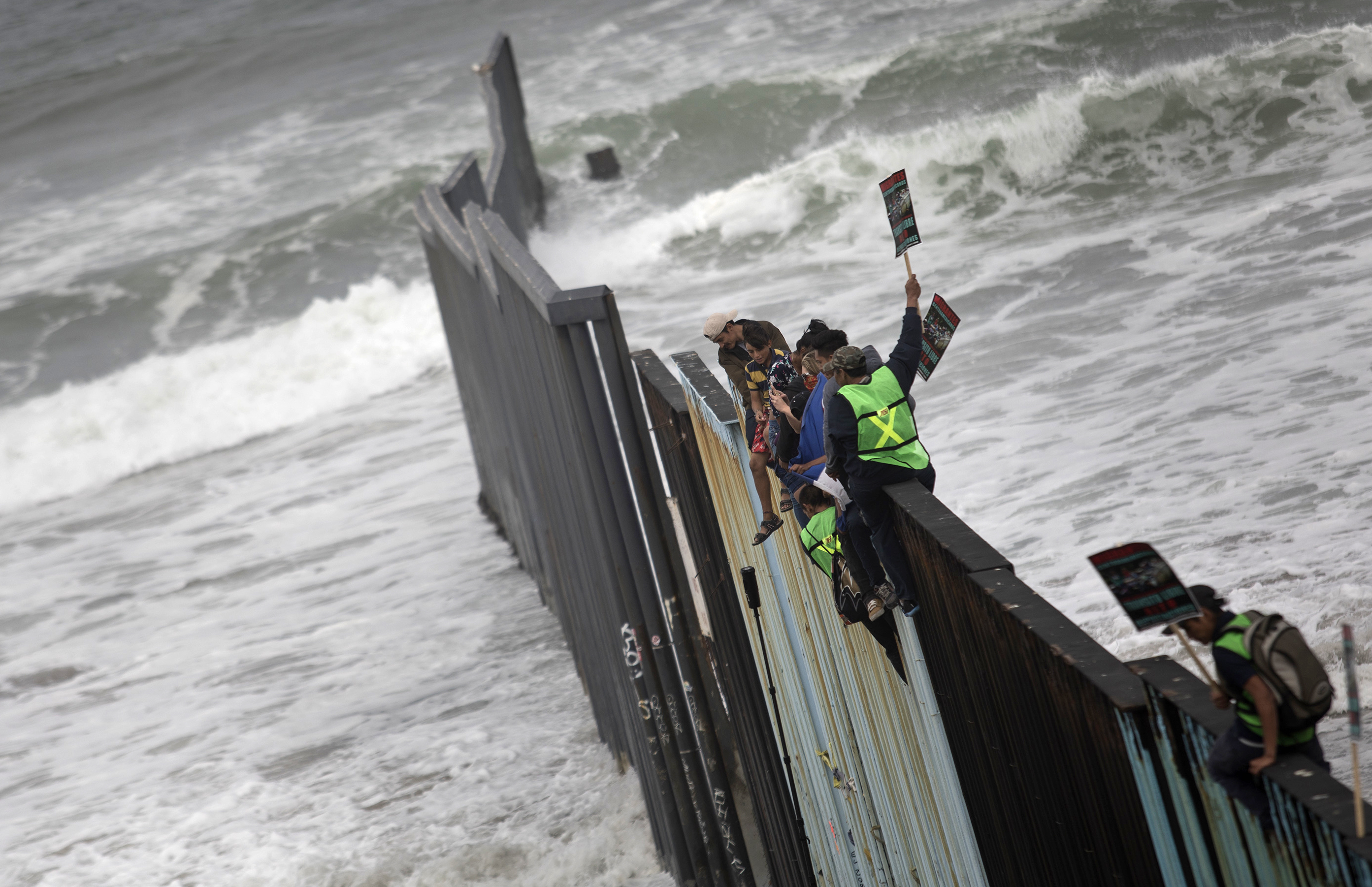 Los migrantes sobre la valla fronteriza en Tijuana (AP Photo/Hans-Maximo Musielik)