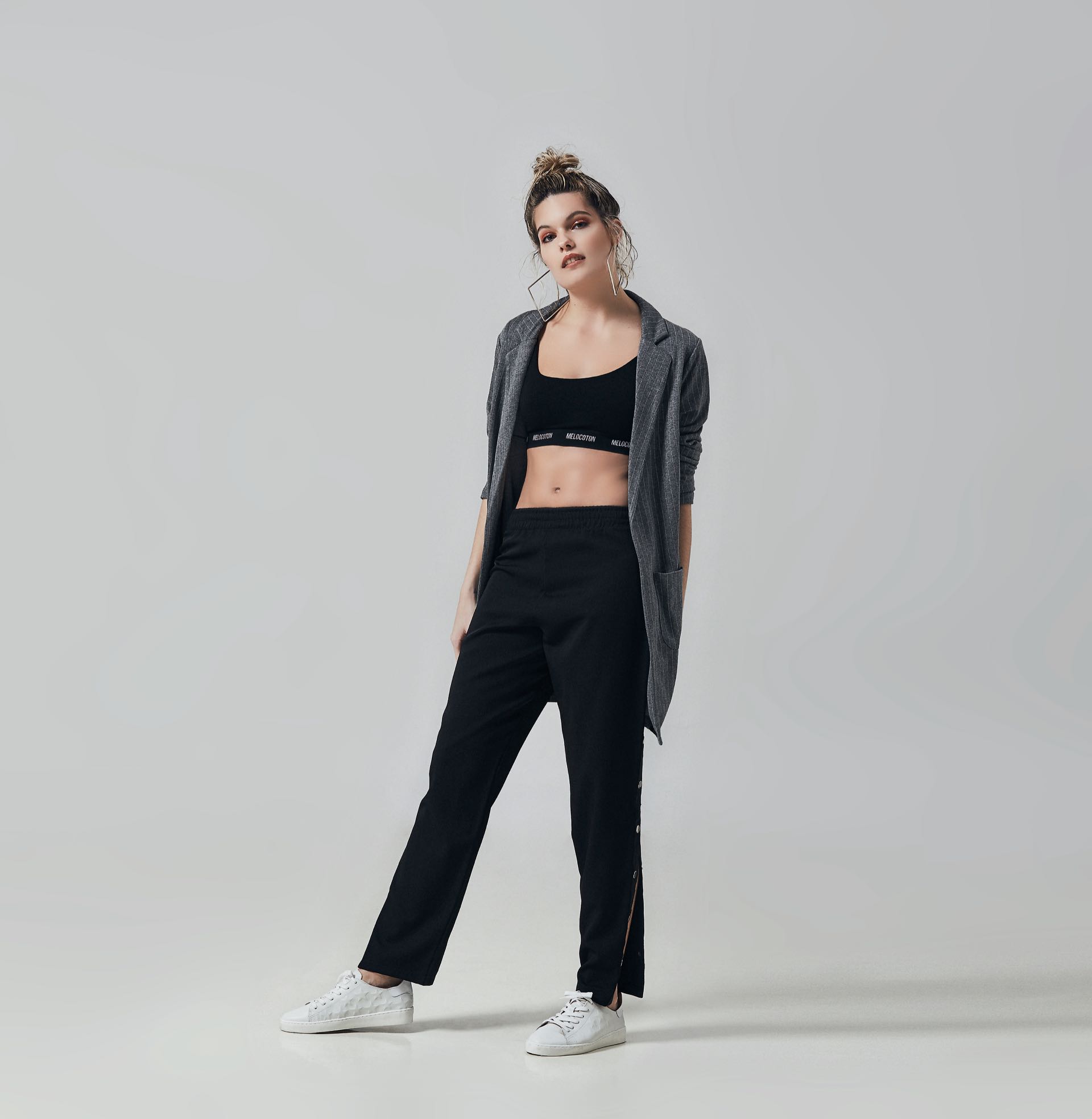 Saco ($ 2.372, La Cofradía), top deportivo ($ 699, Melocotón), pantalón con snaps laterales ($ 1.290, Basement) y zapatillas de cuero con estrellas ($ 1.990, a pie).