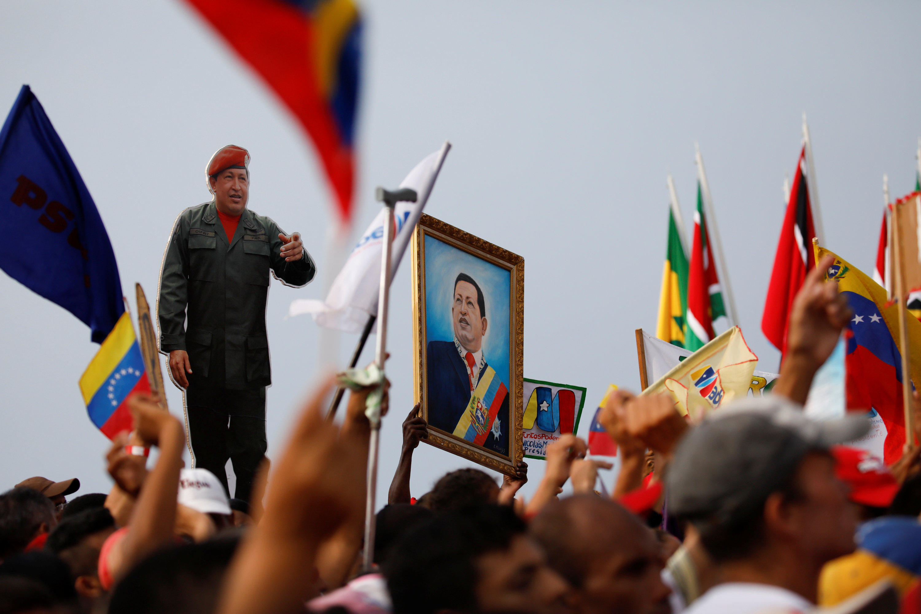 Militantes chavista muestran cuadros de Hugo Chávez durante el acto en La Guaira (REUTERS/Carlos Garcia Rawlins)