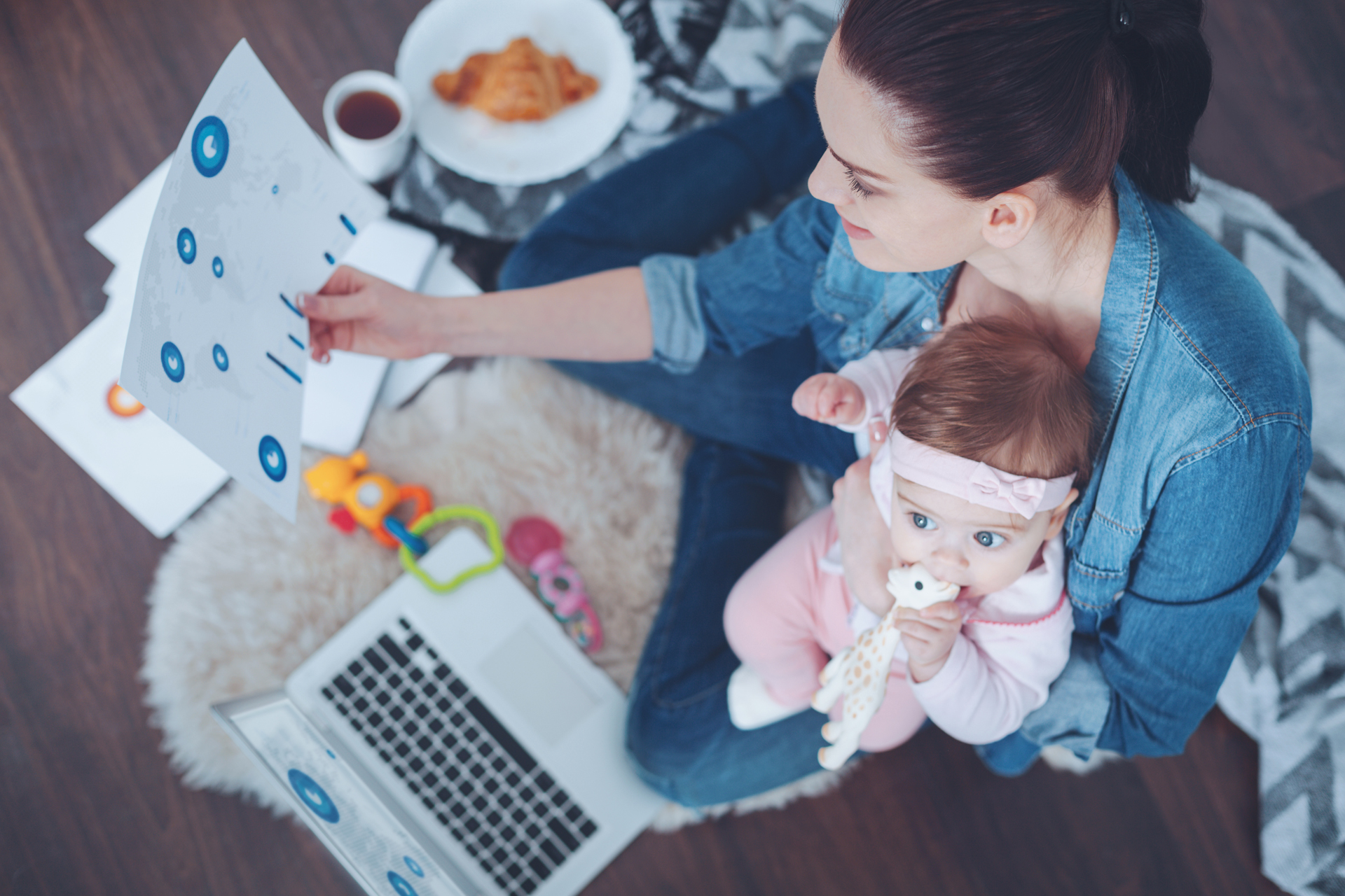 Pleasant atmosphere. Delighted attractive young mother looking at the diagram and smiling while enjoying working at home
