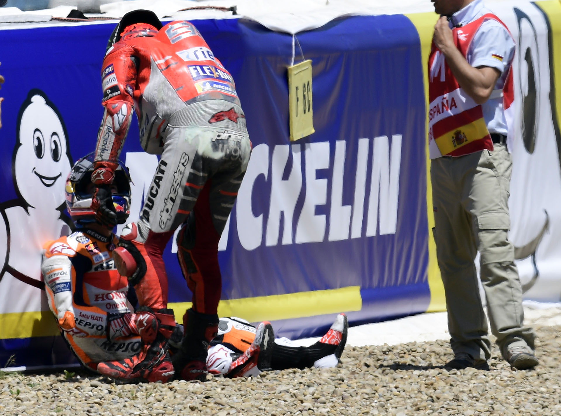 Dani Pedrosa sentado en el piso, muy dolorido tras volar por el aire, hablando con Jorge Lorenzo (AFP)