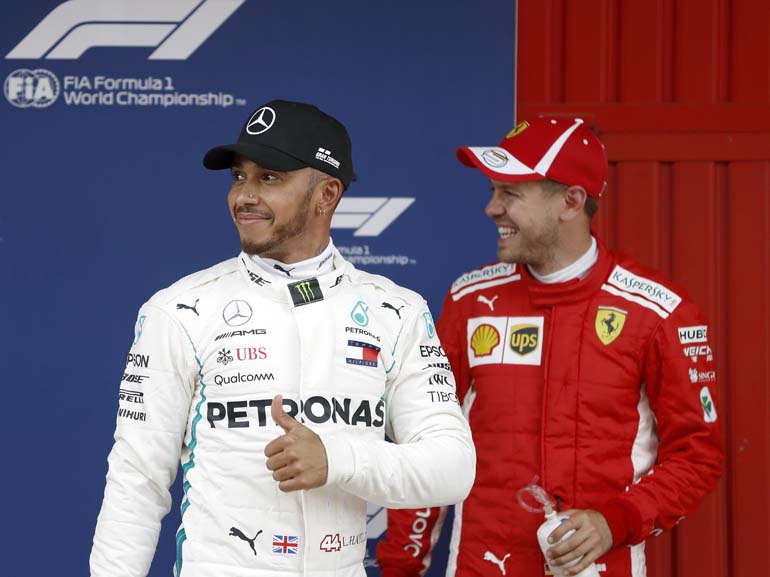 El piloto británico de Mercedes, Lewis Hamilton (i) , que consiguió la pole, junto al piloto alemán de Ferrari, Sebastian Vettel, que fue tercero (d), celebran los puestos obtenidos en los entrenamientos oficiales de la Fórmula Uno en el Circuit de Barcelona-Catalunya (EFE)