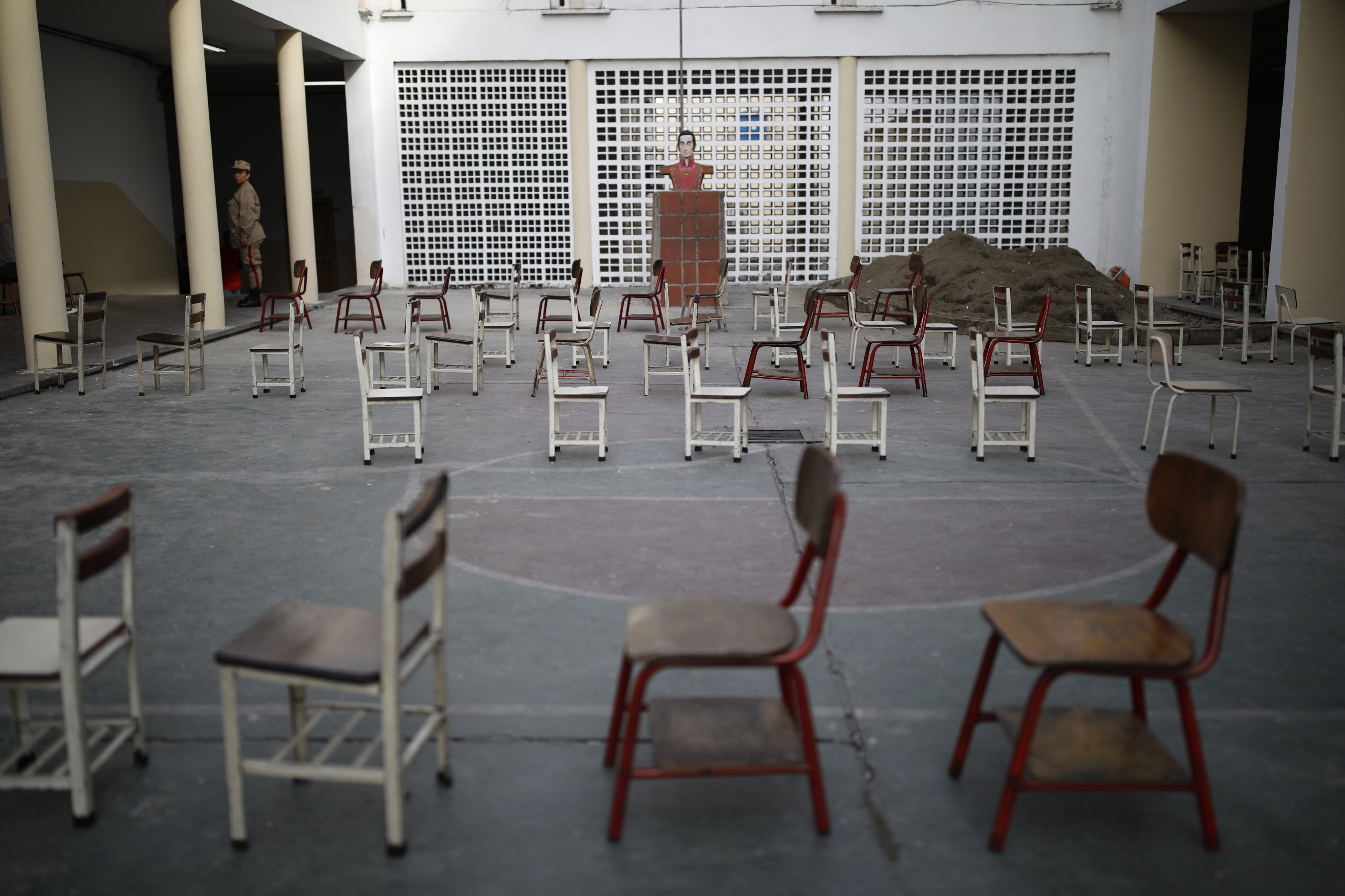 Un miembro de la milicia monta guardia ante las sillas donde se hace la fila, vacías ante la falta de votantes en Caracas (Reuters)