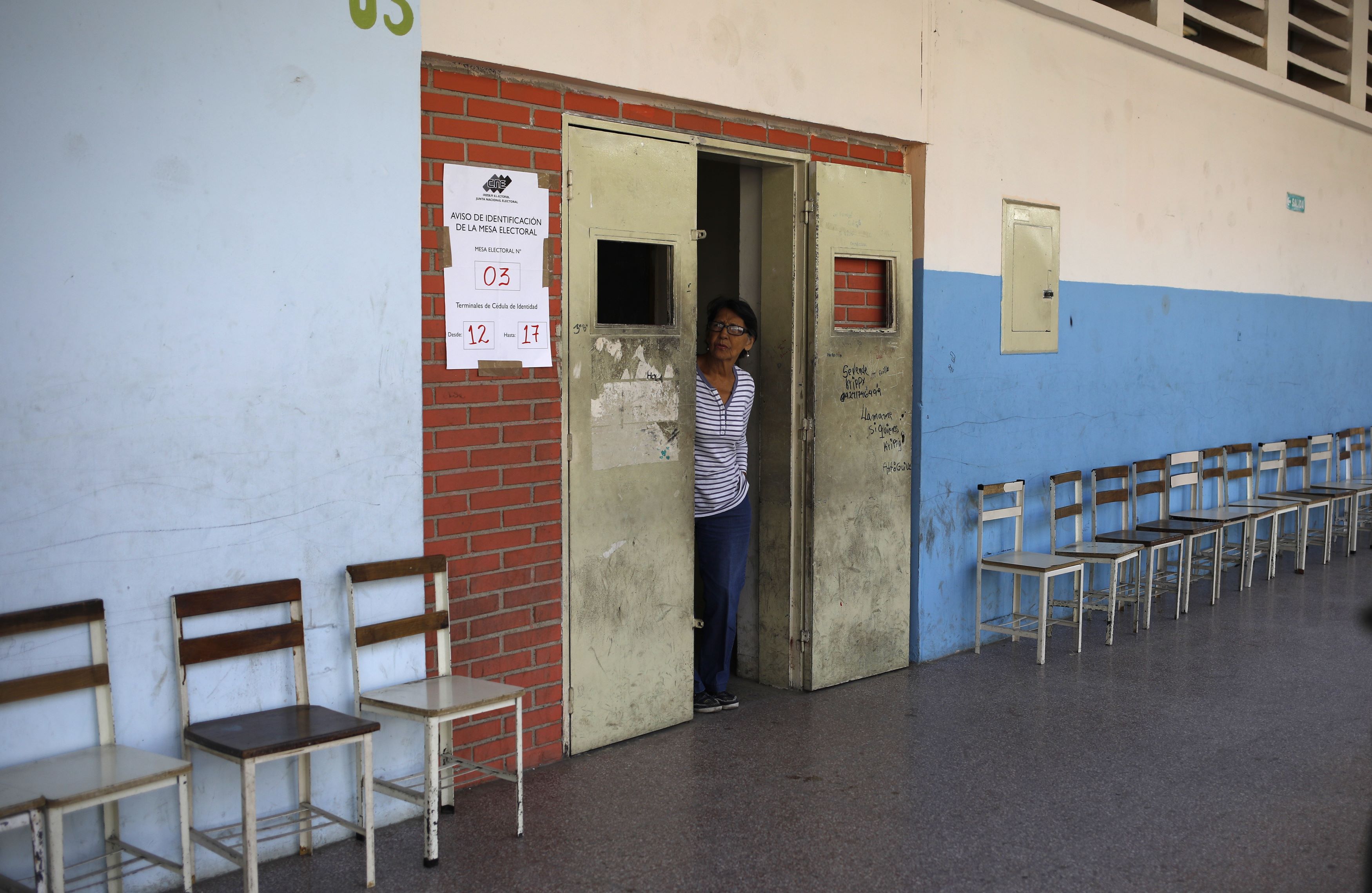 Una mujer se asoma para ver si algún votante se acerca a la mesa