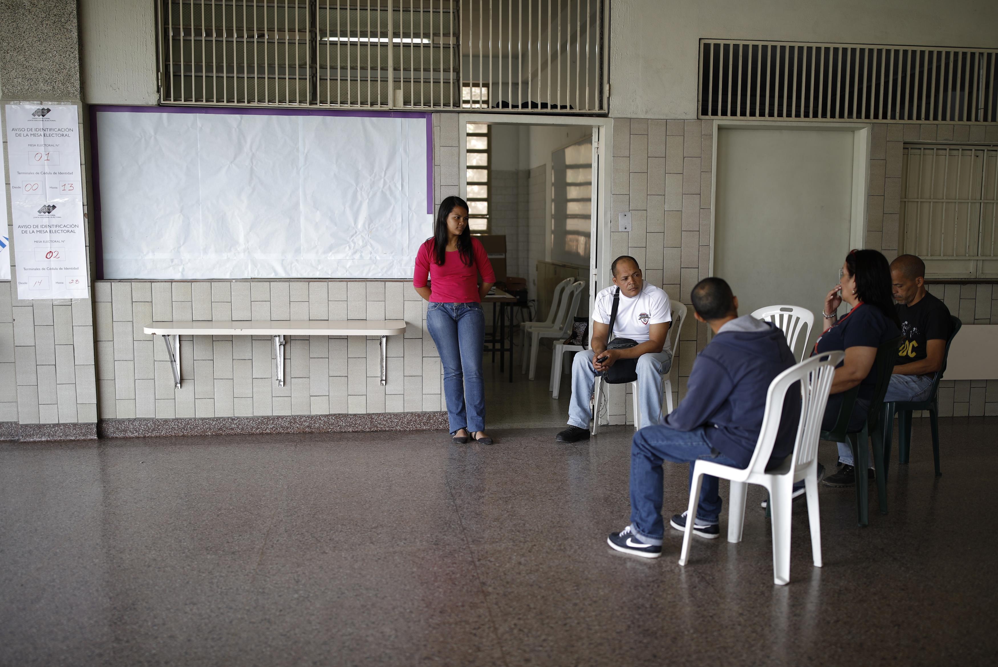 Miembros de una mesa conversan y se distraen mientras esperan a votantes (Reuters)