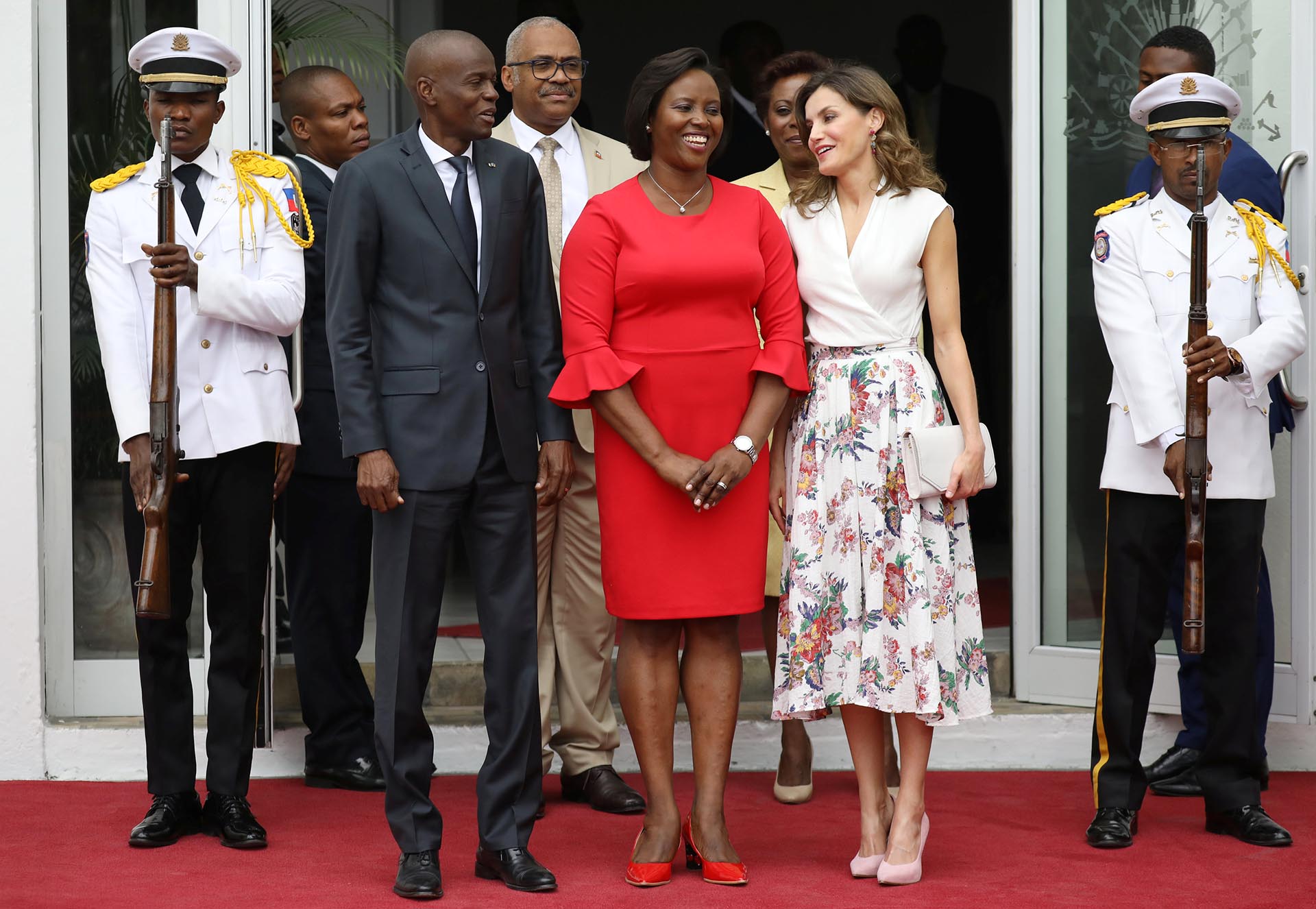 Letizia, acompañada por el presidente de Haití, Jovenel Moise, y su mujer. La monarca eligió un look sencillo pero elegante, acorde a un compromiso diurno. Su look estaba compuesto por una blusa cruzada blanca y una maxi falsa estampada