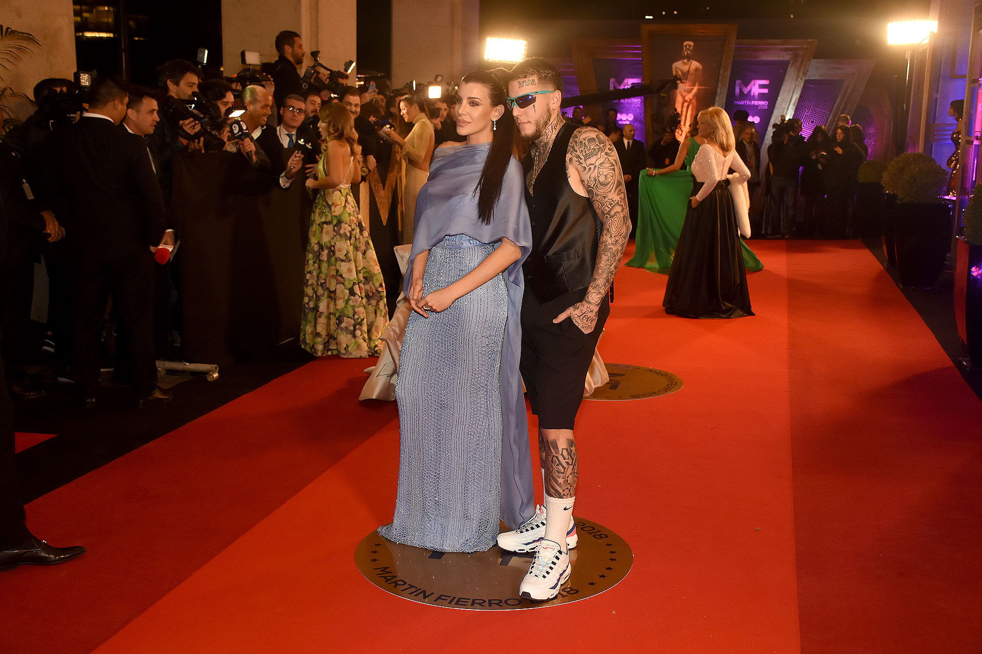Charlotte Cannigia en celeste con diseño de Claudia Arce bordado de pailletes y chal de seda. Alex impactó con bermudas, chaleco de raso y zapatillas deportivas con medias 3/4.