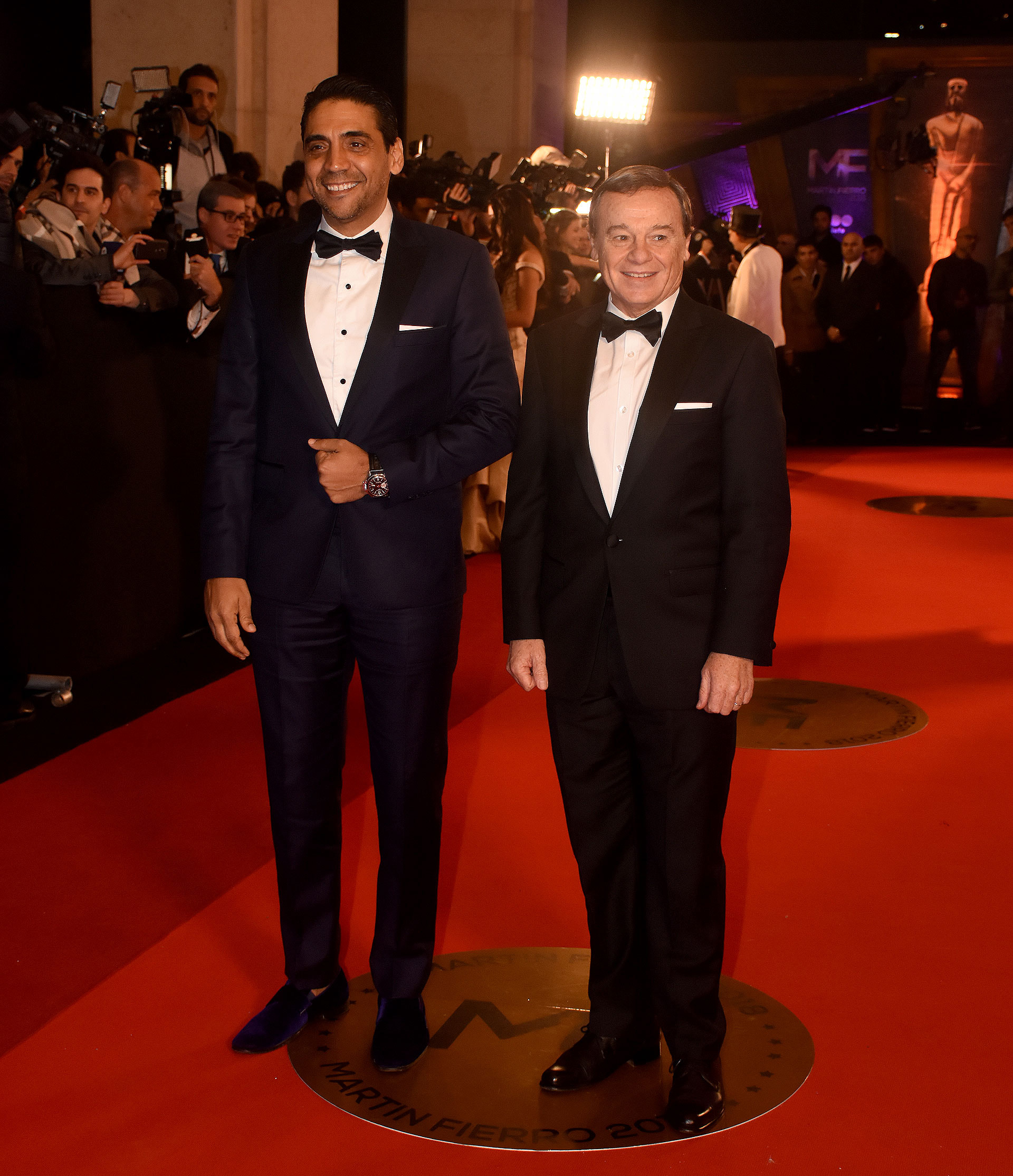 Coco Fernández en smoking azul con mocasines de terciopelo a tono junto a Pablo Codevila en un clásico black tie con moño negro y zapatos de cuero.