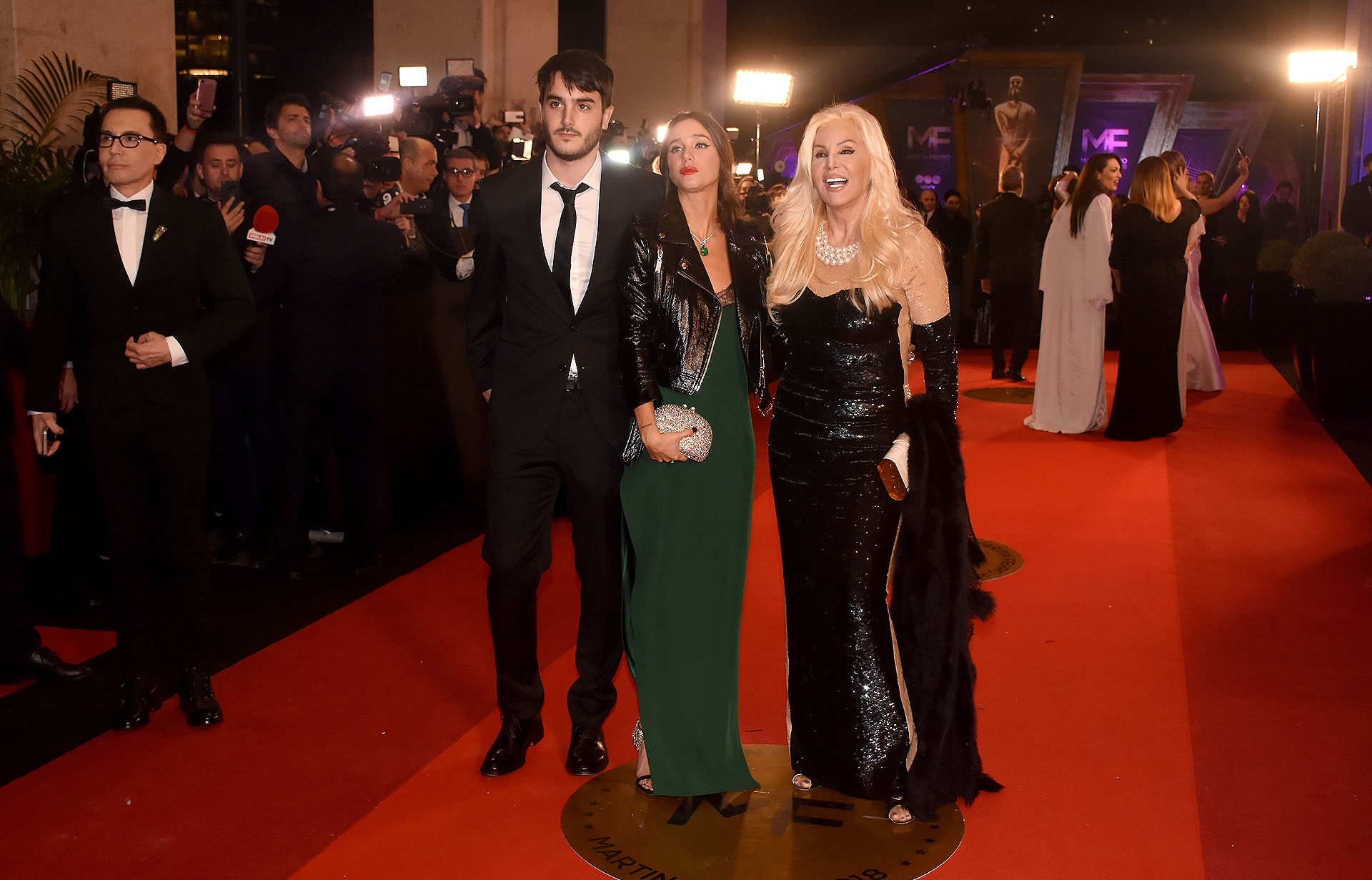 Susana Giménez vestida by Michael Kors junto a su nieta Lucía Celasco by Evangelina Bomparola, con vestido largo en verde inglés con detalle de encaje negro, sandalias con cristales y clutch de brillantes. Manuel Celasco con smoking con corbata negra y camisa blanca.